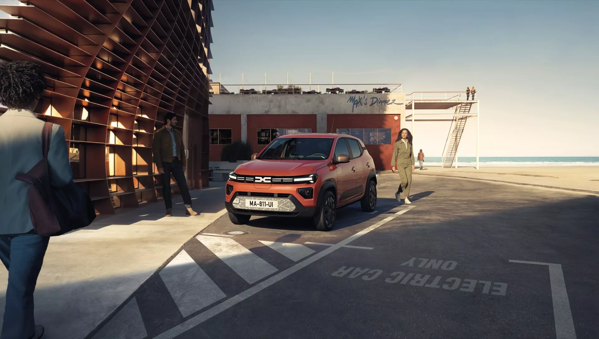 Facelift Dacia Spring 2024 v dynamickém městském prostředí, předvádí moderní LED světlomety, aerodynamickou přední mřížku a slitinová kola z trojčtvrtečního pohledu.