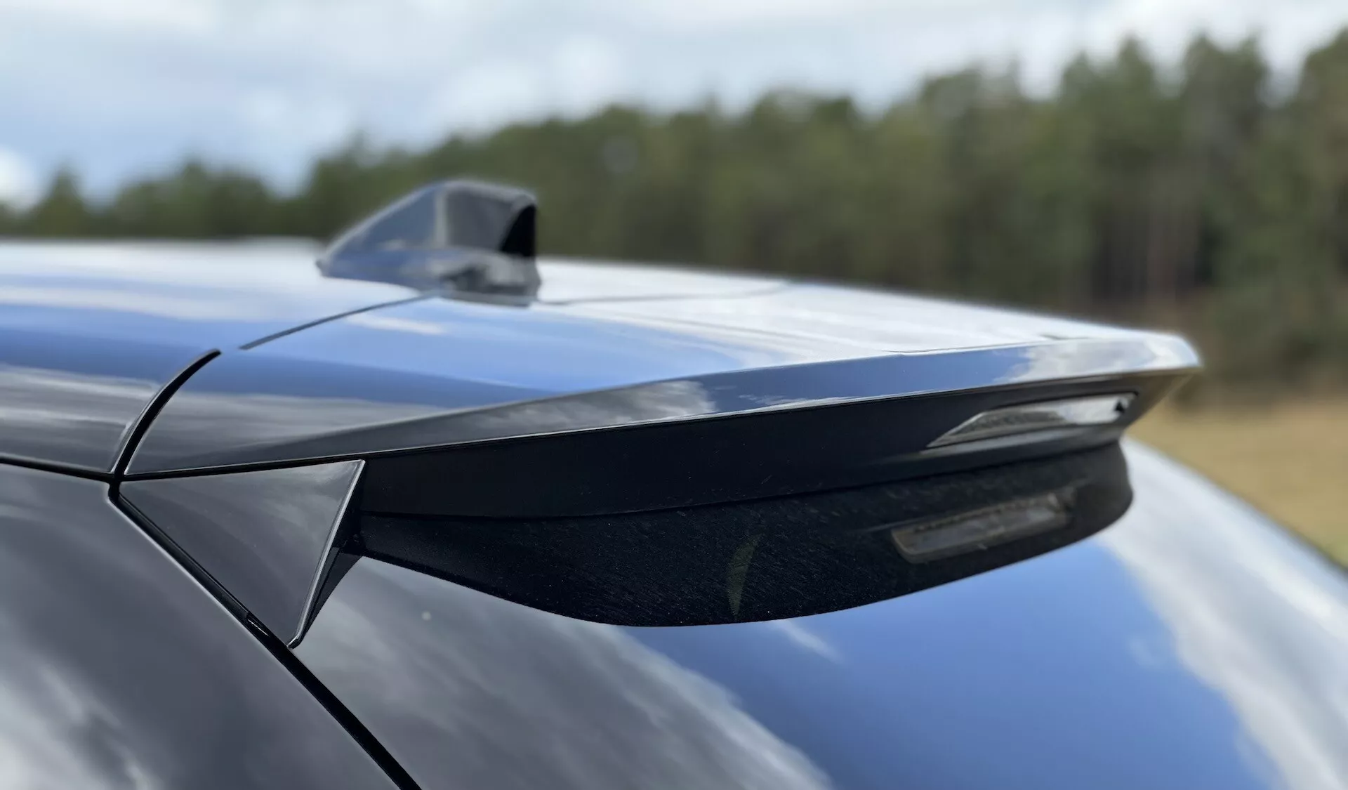 Detailní pohled na zadní spoiler a žraločí ploutev anténu DS Automobiles DS-3 2023, zdůrazňující aerodynamický design a metalický modrý povrch, pořízený z nízkého úhlu směrem dopředu