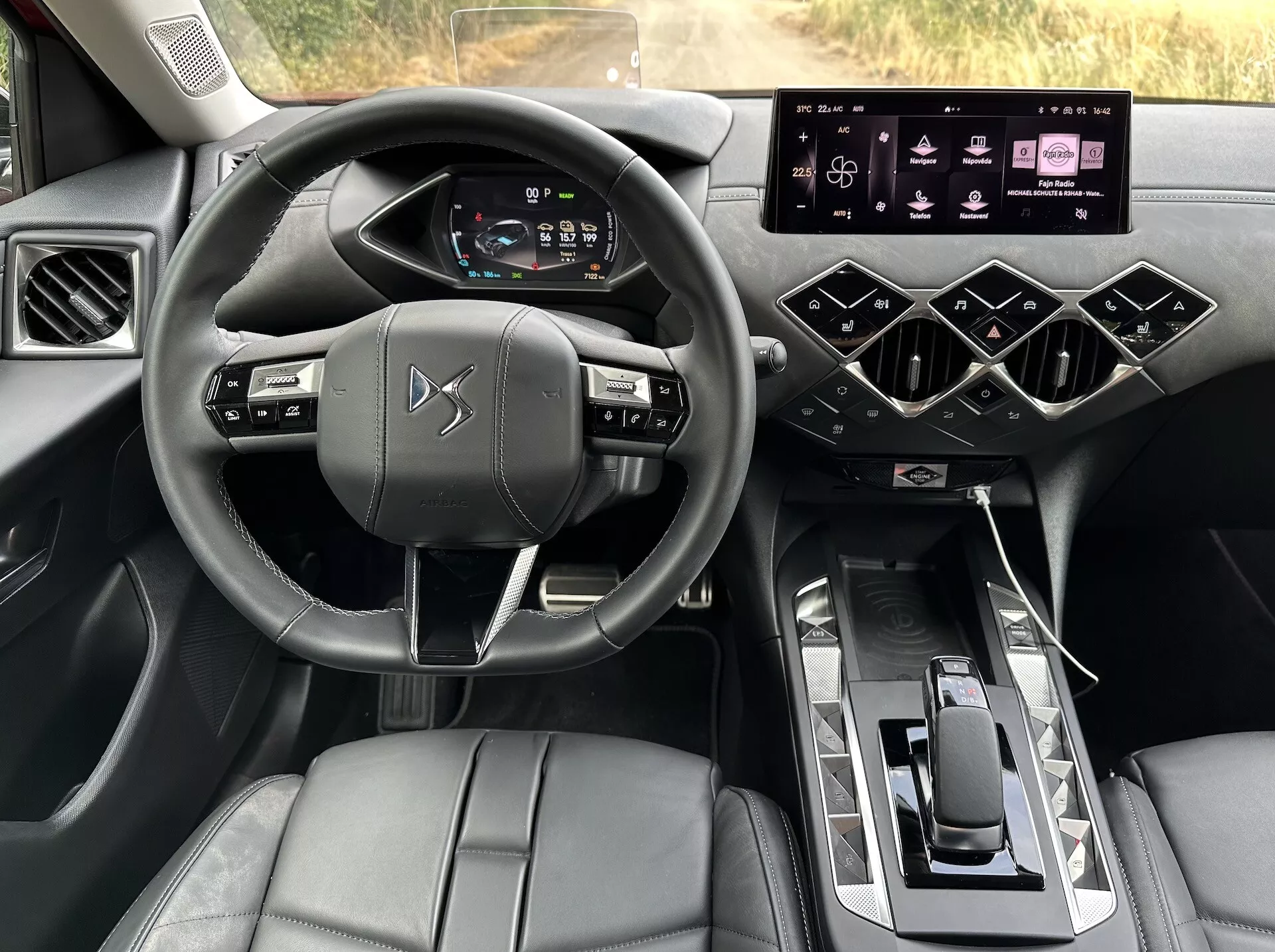 Interiérový pohled na DS Automobiles DS-3 E-TENSE 2023 zdůrazňující pohled řidiče na volant, digitální palubní desku, systém infotainment a středovou konzolu s luxusními povrchy a pokročilými technologickými funkcemi