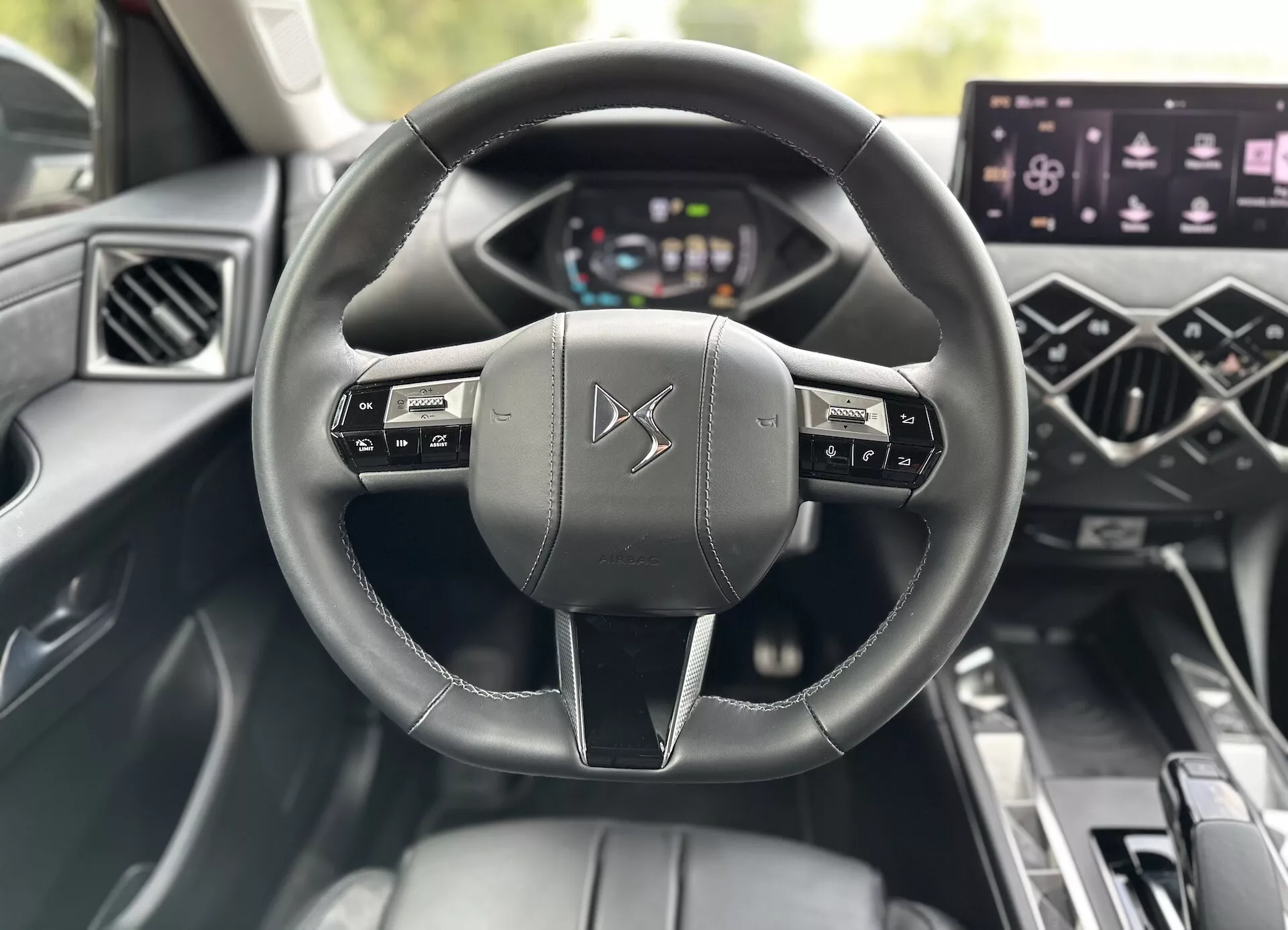 Interiér DS 3 E-Tense 2023 s koženým volantem s tlačítky pro ovládání multimédií, digitálním přístrojovým panelem, centrálním dotykovým infotainment systémem a ovládáním elektrických oken, zdůrazňující pokročilou technologii a design luxusního vozidla