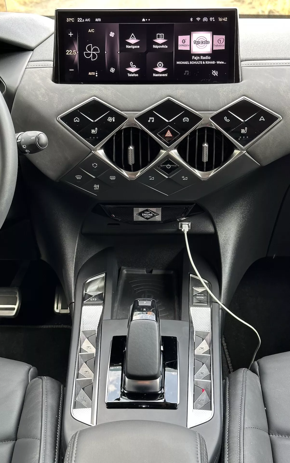 Pohled na interiér DS Automobiles DS-3 E-TENSE 2023, zdůrazňující centrální konzolu s dotykovým infotainment displejem, stylové ventilační otvory, moderní řadicí páku a sedadla z prémiové kůže.