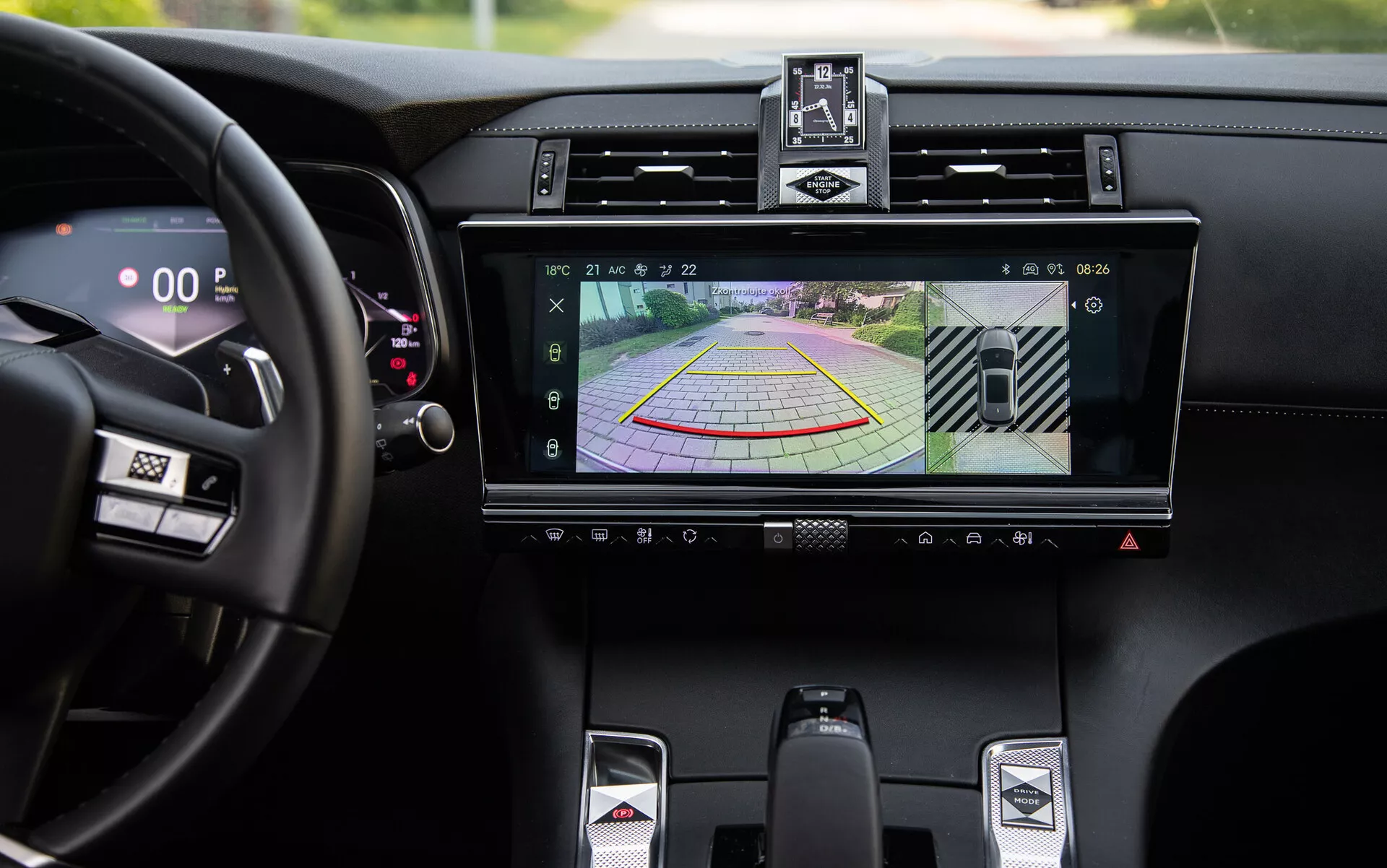 Detail luxusního interiéru DS-7 2022 s infotainment systémem s displejem zadní kamery a dynamickými pokyny pro parkování, centrálními větracími otvory, tlačítky klimatizace, sportovní pákou převodovky a digitálním rychloměrem