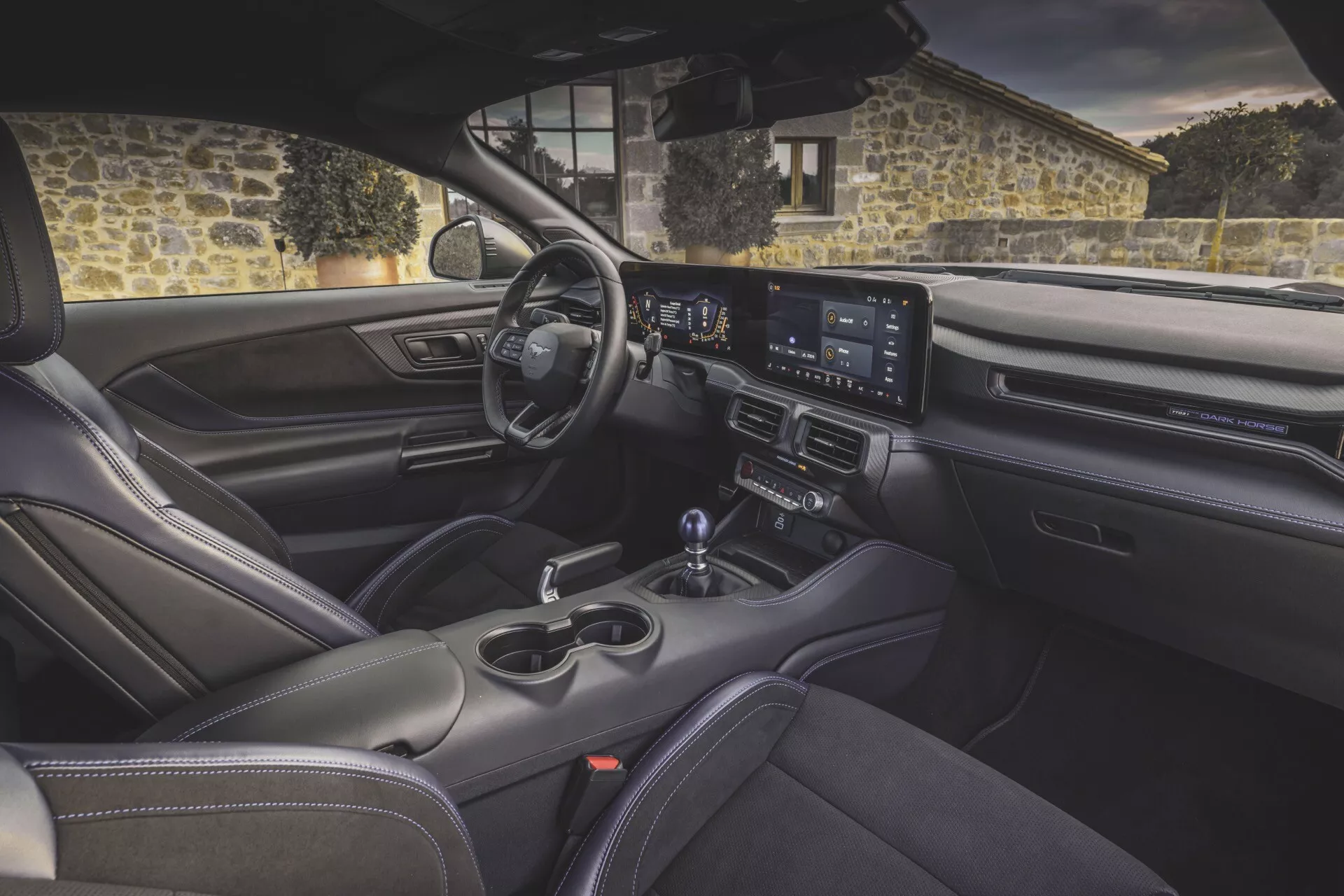 Interiér Ford Mustang 2. generace pro rok 2024 z pohledu ze zadní části, zobrazující palubní desku, širokoúhlý infotainment, sportovní sedadla a pokročilé funkce pohodlí