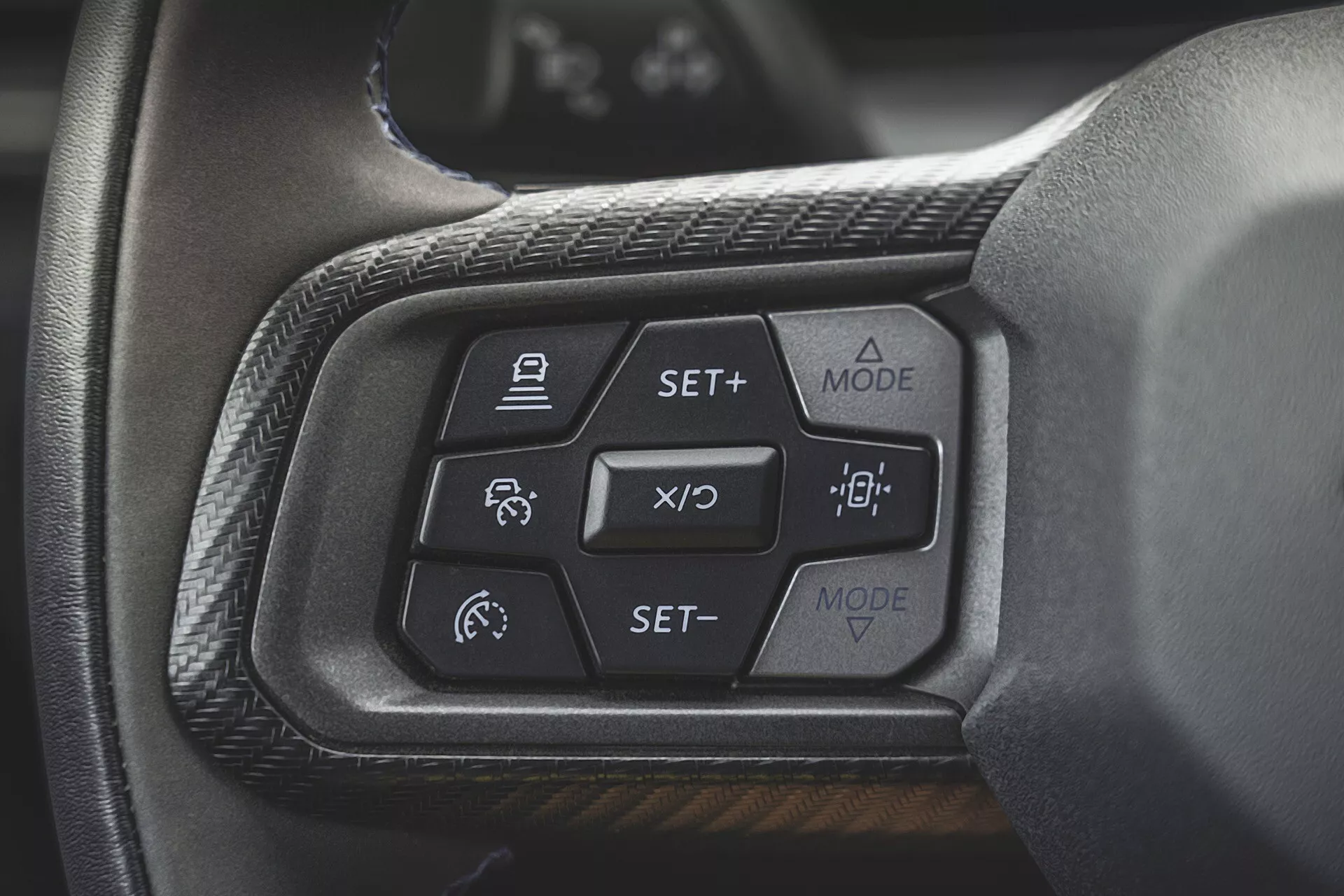 Detailní pohled na ovládací prvky na volantu Ford Mustang druhé generace roku 2024 se zaměřením na adaptivní tempomat, asistent udržování jízdního pruhu a tlačítka pro ovládání režimu displeje na palubní desce z pohledu řidiče