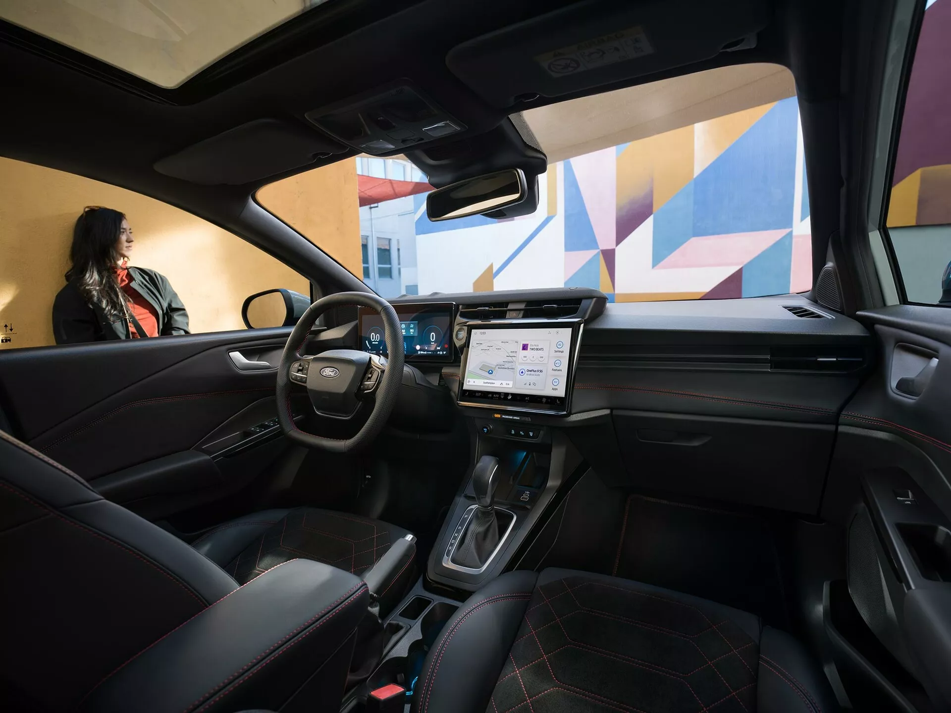 Interiér Fordu Puma facelift 2024 z pohledu zadního cestujícího s koženým multifunkčním volantem, digitálním palubním deskou, velkým dotykovým displejem infotainmentu, automatickou řadící pákou na středové konzole, sedadly s prošívanou kůží a střešním oknem