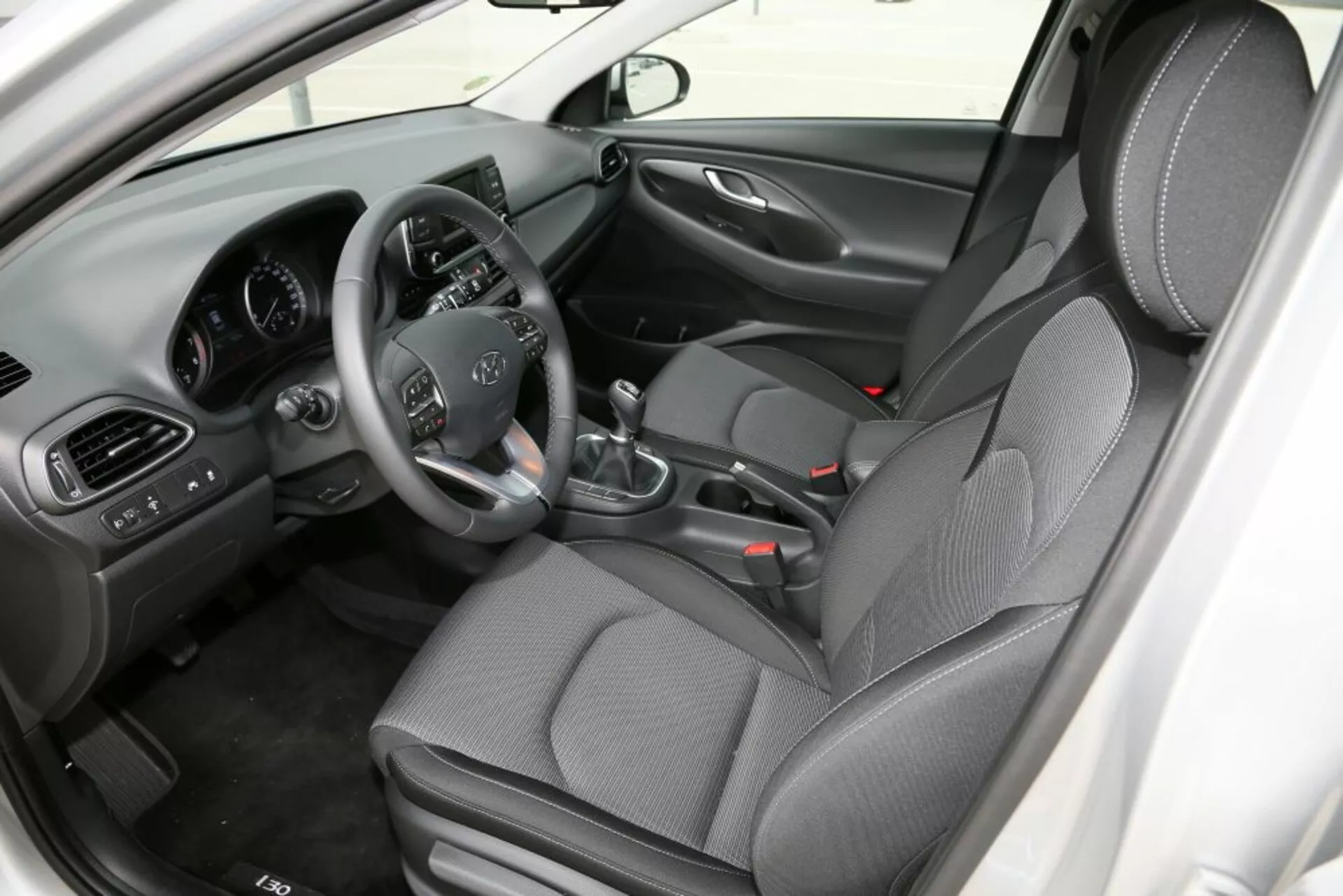 Interiér Hyundai i30 2017 (i30-N) s důrazem na přední kabinu, zobrazení sedadla řidiče s ovládáním na volantu, ruční převodovkou, centrální konzolou a sedadly s potahem se vzorem