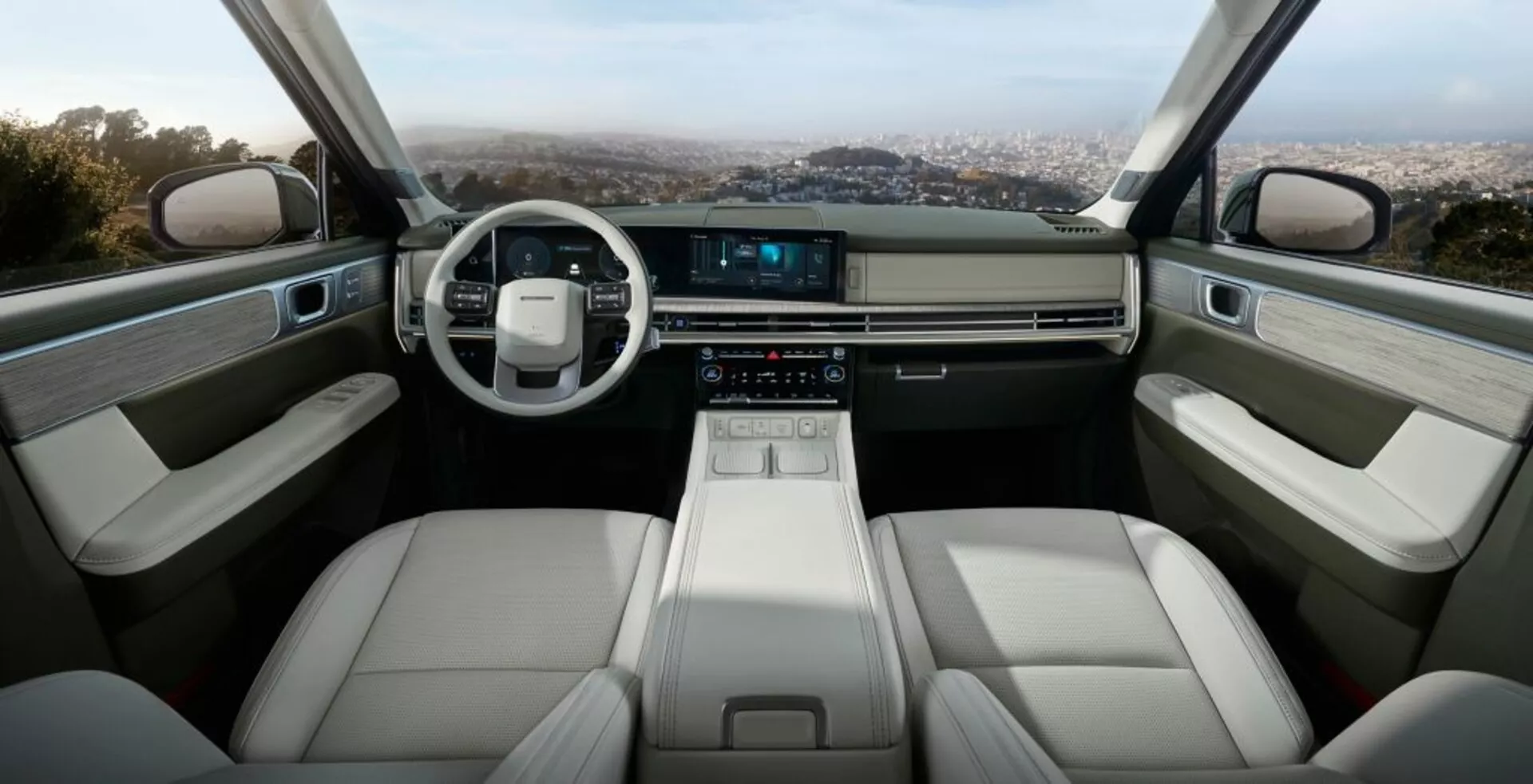 Interiér Hyundai Santa Fe 2024 (5. generace), který představuje přední kabinu s moderní minimalistickou přístrojovou deskou, dvouramenným koženým volantem a dotykovým displejem infotainmentu. Středová konzole obsahuje elegantní elektronický volič převodových stupňů, držáky na nápoje a úložné přihrádky. Přední sedadla jsou čalouněna světlejší kůží, což zajišťuje pohodlí a ergonomii. Interiér dveří zahrnuje opěrky, ovládací panely pro elektrická okna a další úložné prostory, vše vyrobené z materiálů vysoké kvality. Celkový design vyzařuje luxus, technologie a prostornost.