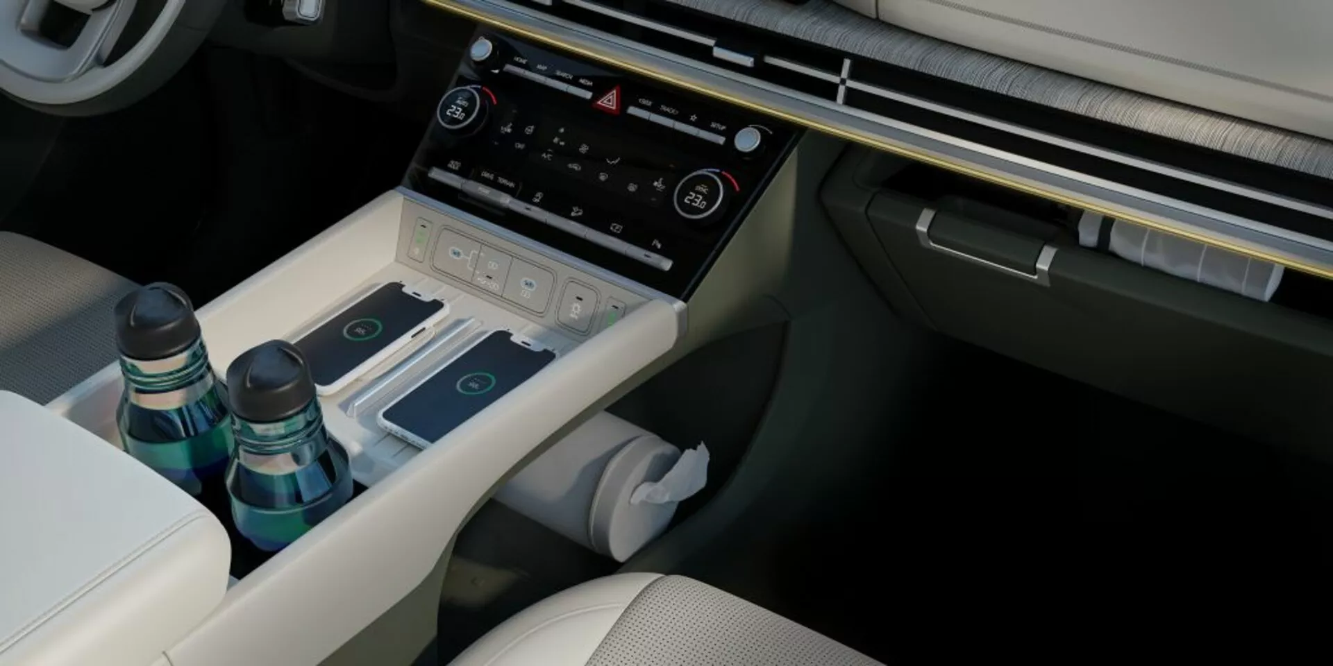 Interiér pohled na Hyundai Santa-Fe 2024 (5. generace) středovou konzoli z mírně vyvýšeného úhlu, zachycující řidičovo sedadlo ve světlém čalounění s detaily šití, otevřenou centrální opěrku s úložným prostorem pro dvě láhve a dřevěným vzhledem, částečně viditelnou bílou hygienickou utěrku pod středovou konzolí, elegantní volič převodovky na převodním tunelu, různé ovládací tlačítka pro jízdní režimy nebo nastavení odpružení, pokročilý klimatický systém s obrazovkou a hmatovými tlačítky a spodní okraj infotainment systému. Sedadlo spolujezdce je podobné řidičovu sedadlu v čalounění. Obrázek zdůrazňuje luxusní interiérový design vozidla, prémiové materiály a technologické prvky jako infotainment, klimatizaci, úložná řešení, elektronický volič převodovky a přizpůsobitelná nastavení jízdy.