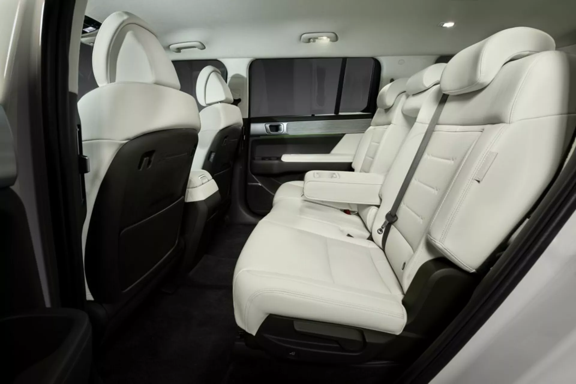 Luxusní interiér Hyundai Santa Fe 2024 (pátá generace) se zaměřením na zadní sedadla pro cestující. Světle zbarvené kožené sedačky s kontrastními akcenty, výsuvná středová konzole s držáky na nápoje, zábavní systém pro zadní sedadla a pokročilé ovládání klimatu a sedadel. Viditelně vysoce kvalitní materiály a řemeslné zpracování zvyšují luxusní pocit.