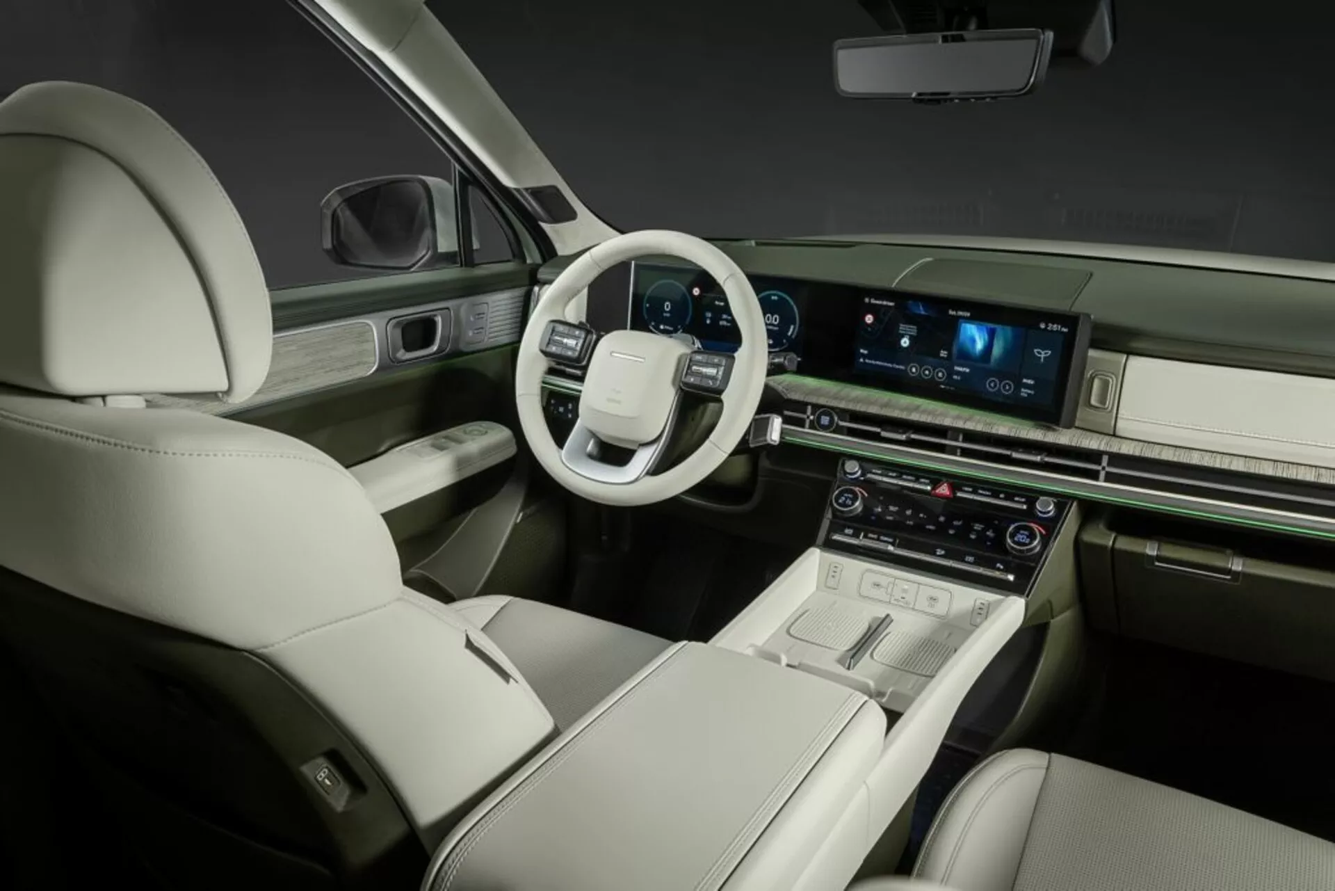 Pohled do interiéru Hyundai Santa Fe 2024 (5. generace) z pravé zadní perspektivy, zobrazující řidičovu stranu. Moderní uspořádání palubní desky zahrnuje multifunkční volant s dotykovými ovládacími prvky. Centrální konzola obsahuje velký horizontální dotykový infotainment systém, pravděpodobně nabízející navigaci, média a nastavení vozidla. Pod ním digitální displeje a ovládací prvky řídí dvouzónový klimatizační systém. Luxusní interiér nabízí kožené čalounění, kontrastní šití a elegantní dekorační prvky, které vyzařují prémiové řemeslné zpracování. Pohodlná a prostorná přední sedadla s elektrickým nastavením zdůrazňují zaměření na komfort cestujících a pokročilé automobilové technologie.