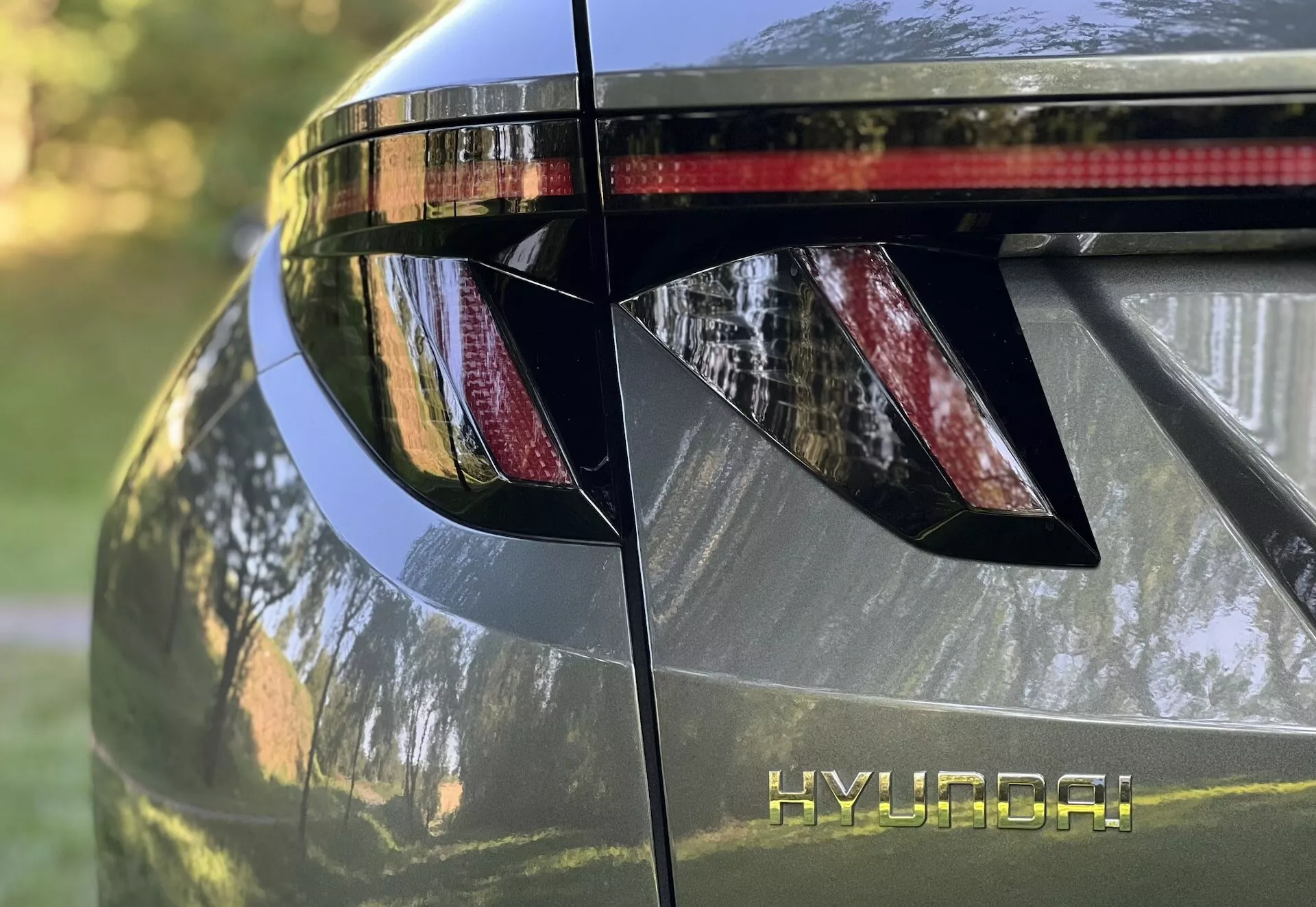 Detailní pohled na zadní část Hyundai Tucson 2020, zahrnující úhlová LED zadní světla, značení HYUNDAI, integrovaný zadní spoiler s brzdovým světlem a lesklý kovový povrch