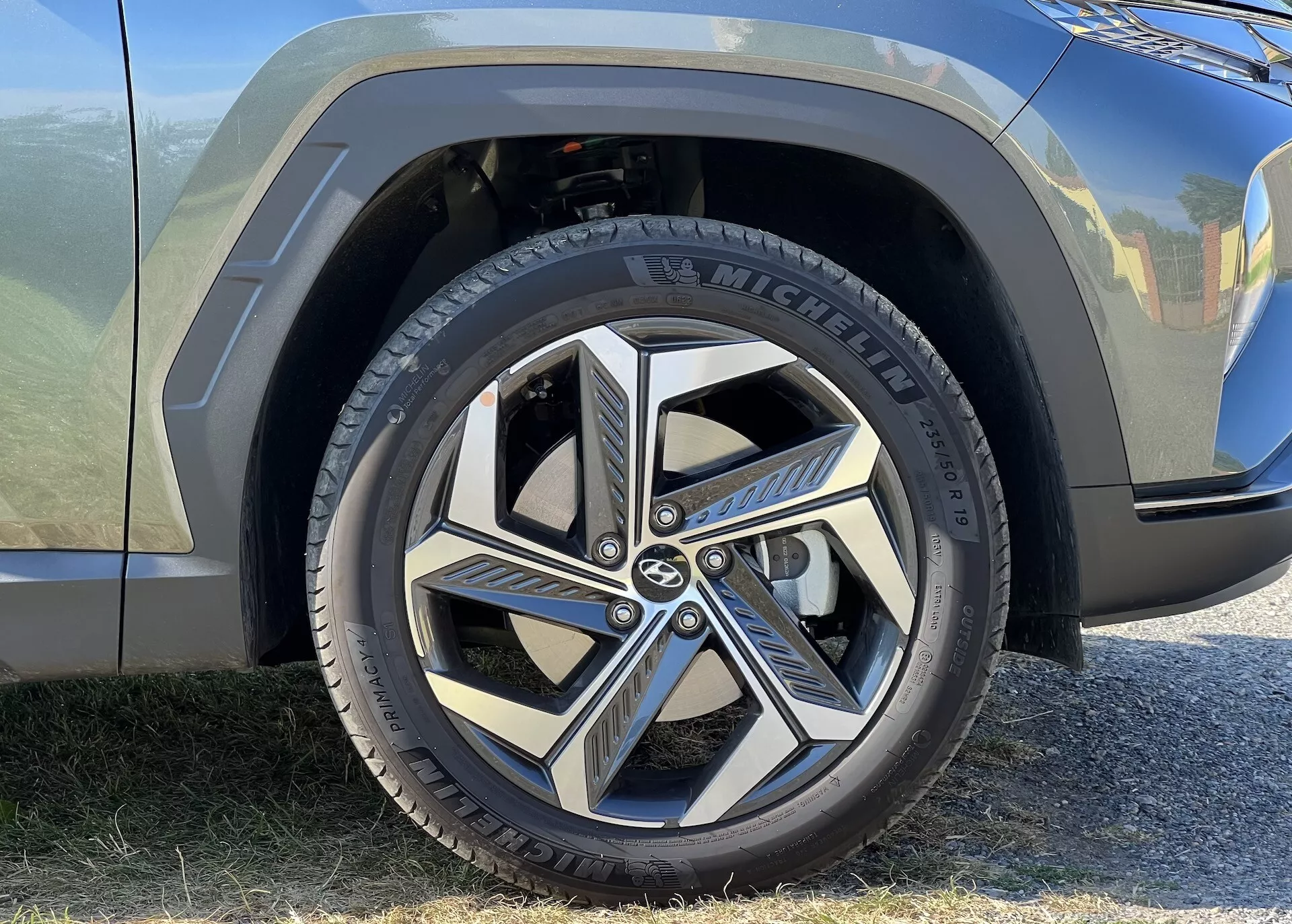 Detailní pohled na přední kolo a částečný blatník Hyundai Tucson 2020, s pneumatikou Michelin a dynamickým designem slitiny s více paprsky, zdůrazňující moderní estetiku a značení automobilu