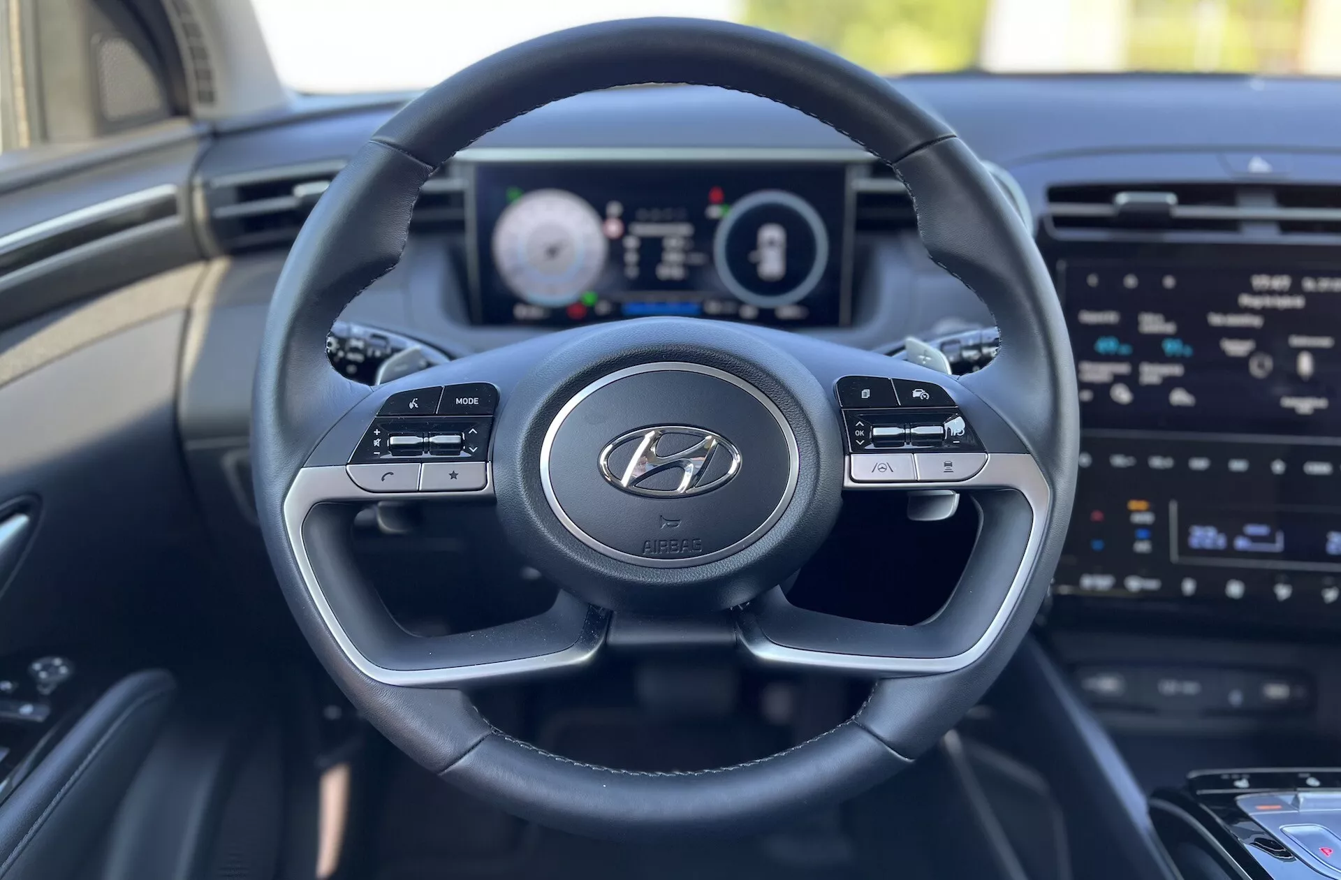 Interiér Hyundai Tucson 2020 z pohledu řidiče ukazující volant s logem Hyundai, digitální přístrojovou desku a obrazovku infotainmentu