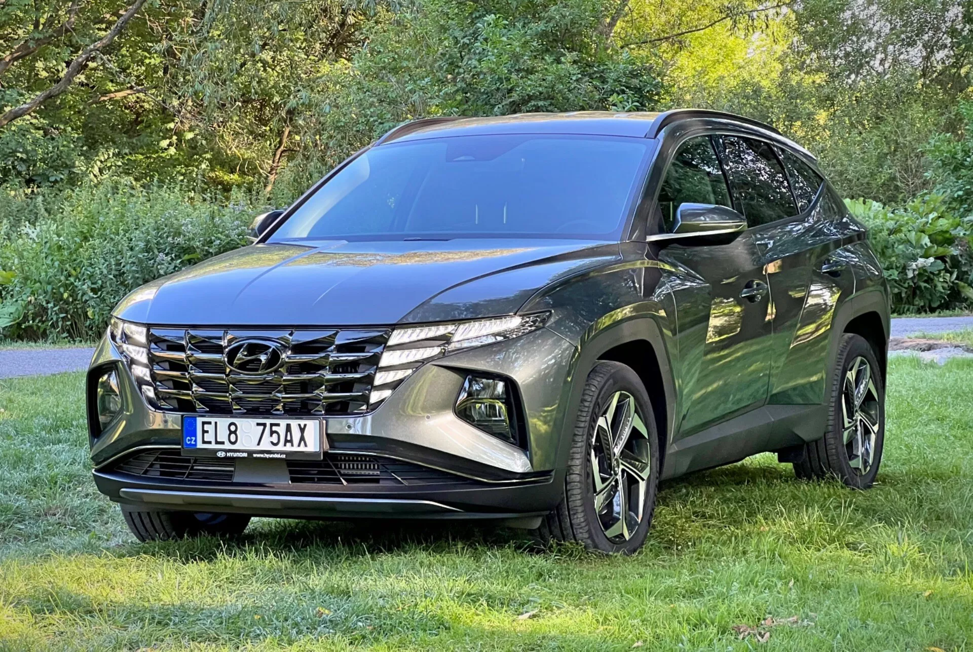 SUV Hyundai Tucson 2020 zaparkované na trávě s pozadím stromů ukazující přední mřížku, LED světlomety a slitinová kola