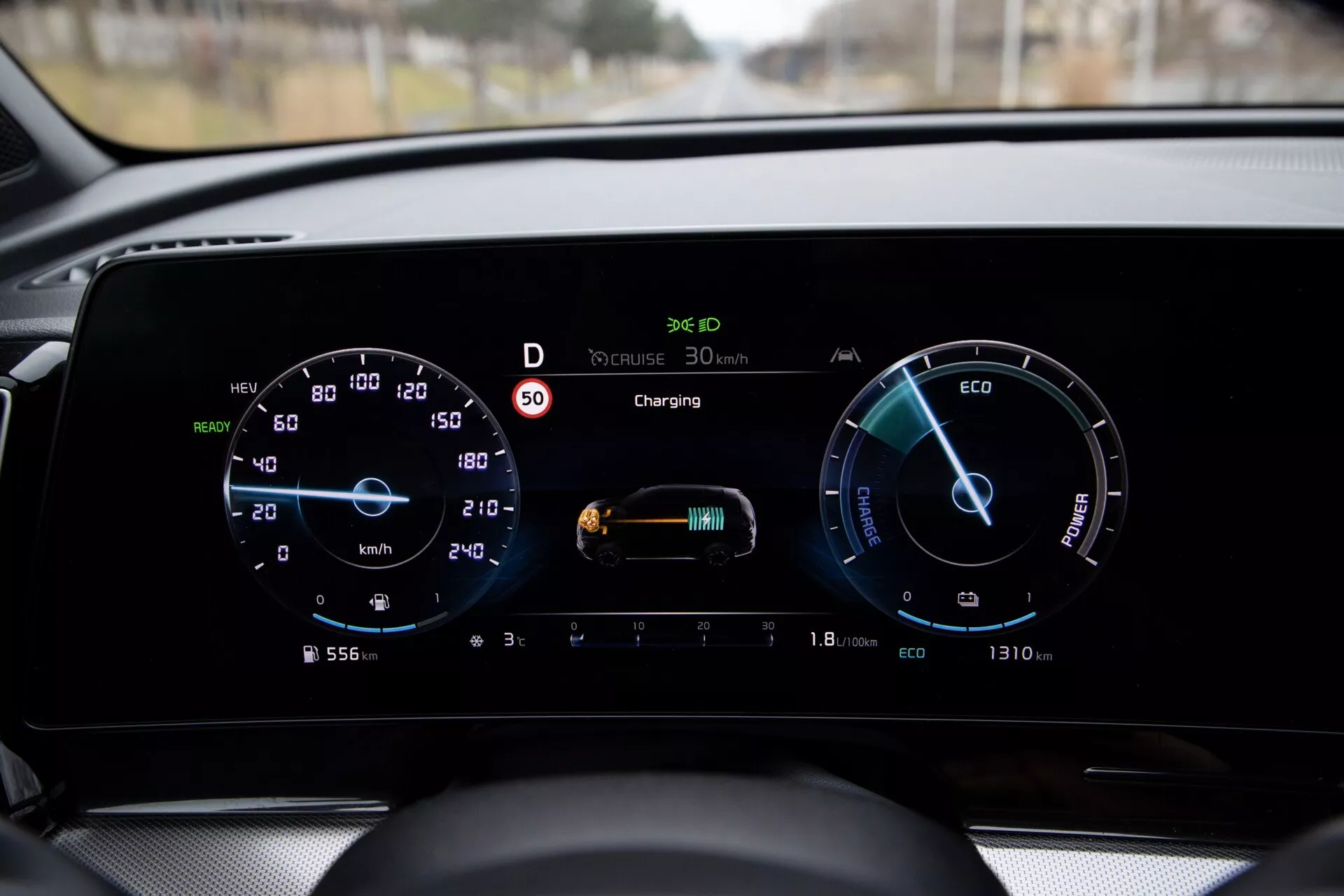 Interiér Kia Sportage NQ5 rok 2022 se zobrazením digitálního palubního desky ukazující tachometr, ukazatel výkonu, stav nabíjení vozidla, indikátor spotřeby energie, režim ECO, tempomat, funkci automatických světlometů a zobrazení venkovní teploty