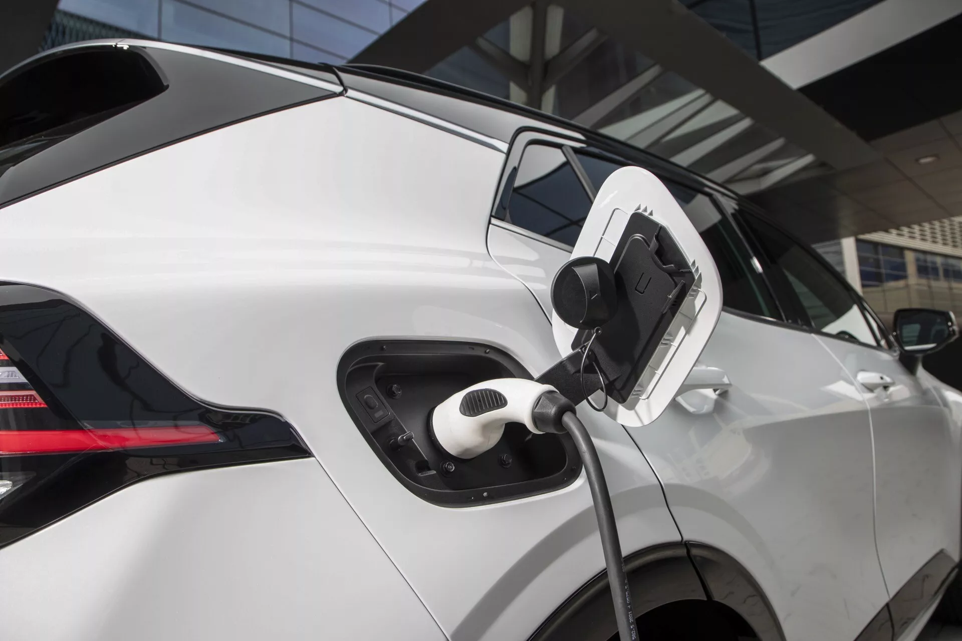 Detailní boční pohled na nabíjecí port elektrického vozidla Kia Sportage 2022 NQ5 s připojeným kabelem, zdůrazňující moderní technologii a designové prvky EV