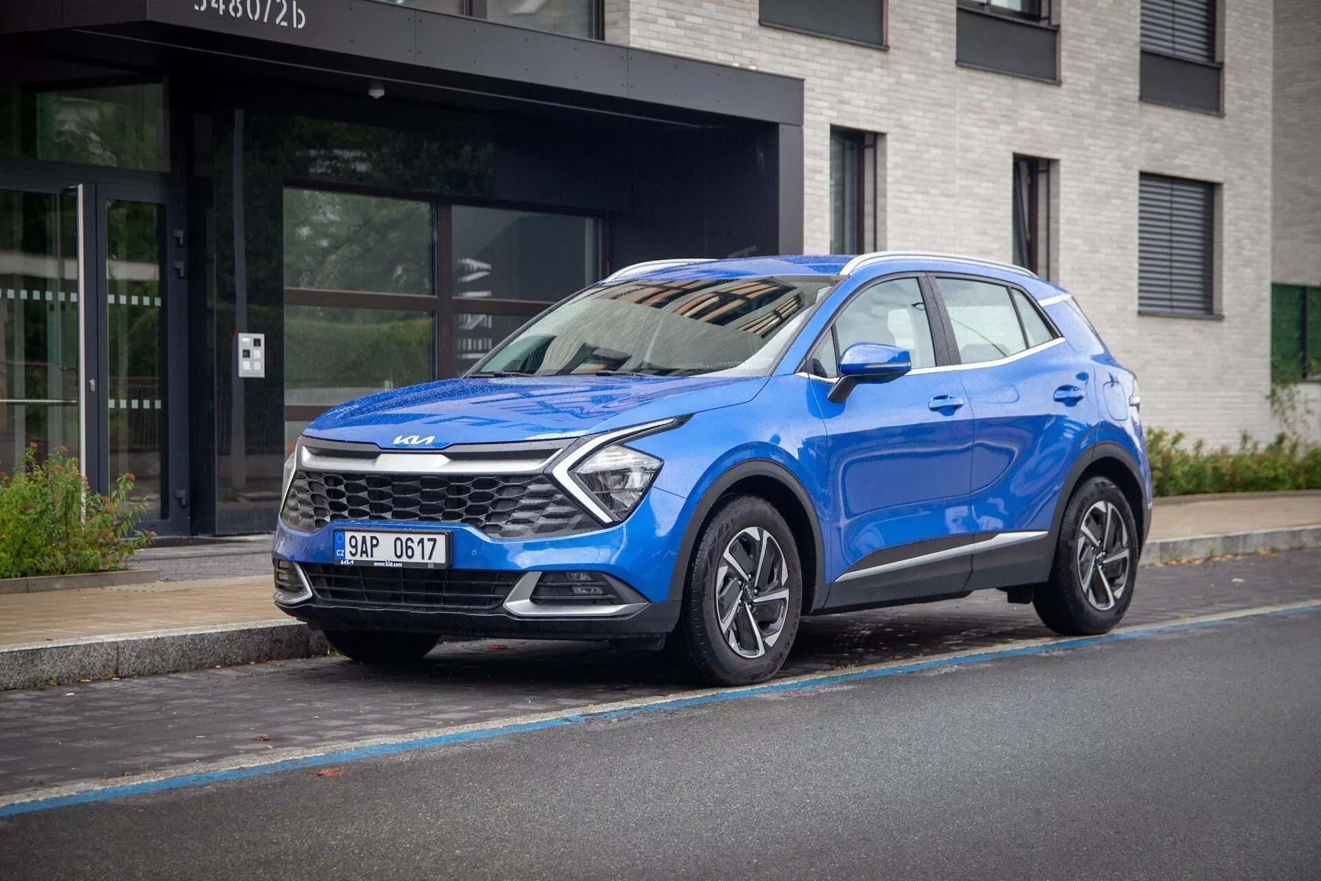 Modré Kia Sportage 2022, s trojčetnou čelní pohledem na městské ulici, zdůrazňující jeho vysokou polohu, LED světlomety, slitinová kola a moderní bezpečnostní technologie.