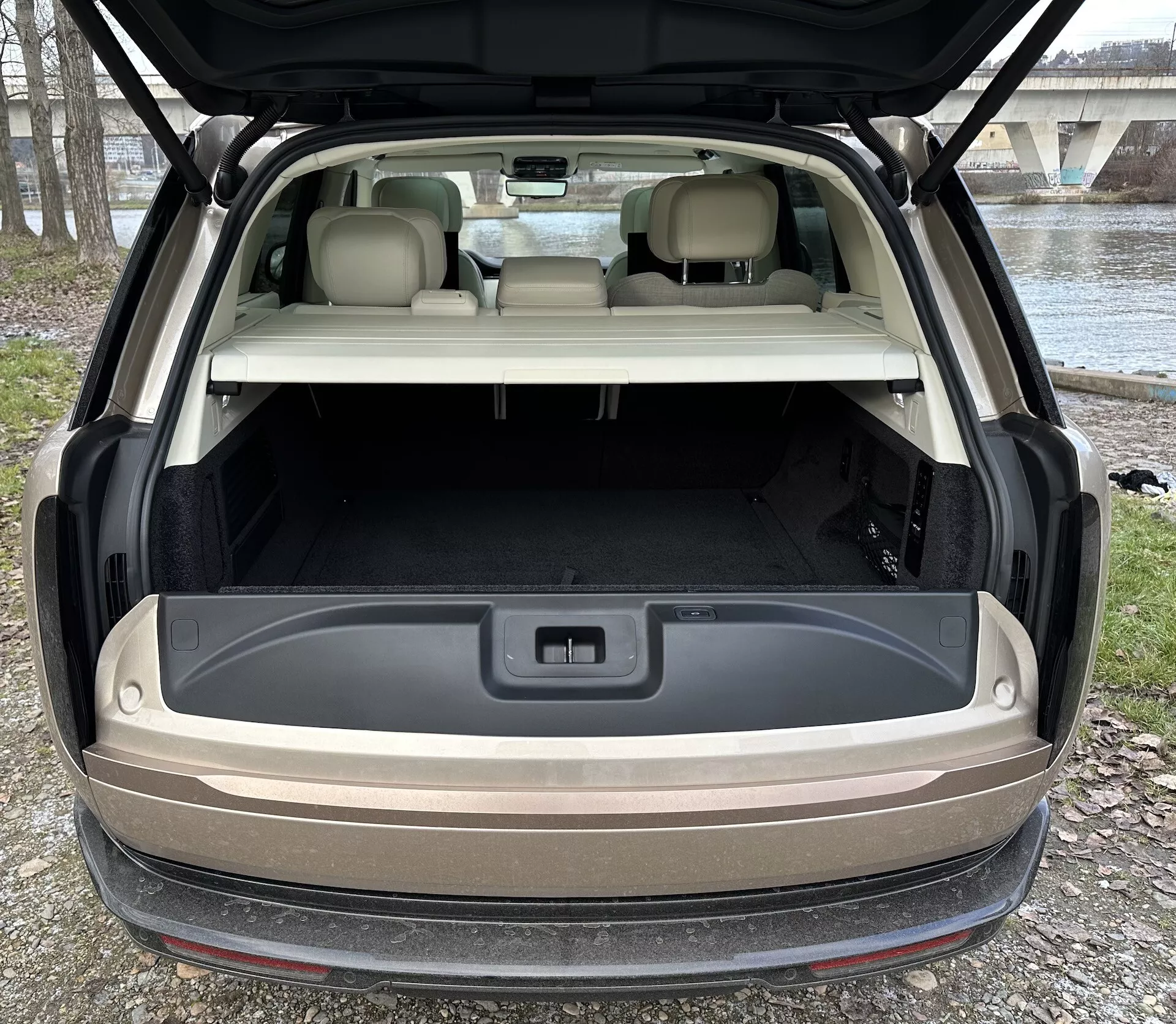 Zadní pohled na Land Rover Range Rover 2021 s otevřeným hatchbackem ukazujícím prostorný nákladní prostor, pokročilé osvětlení a 12voltovou zásuvku v přirozeném venkovním osvětlení