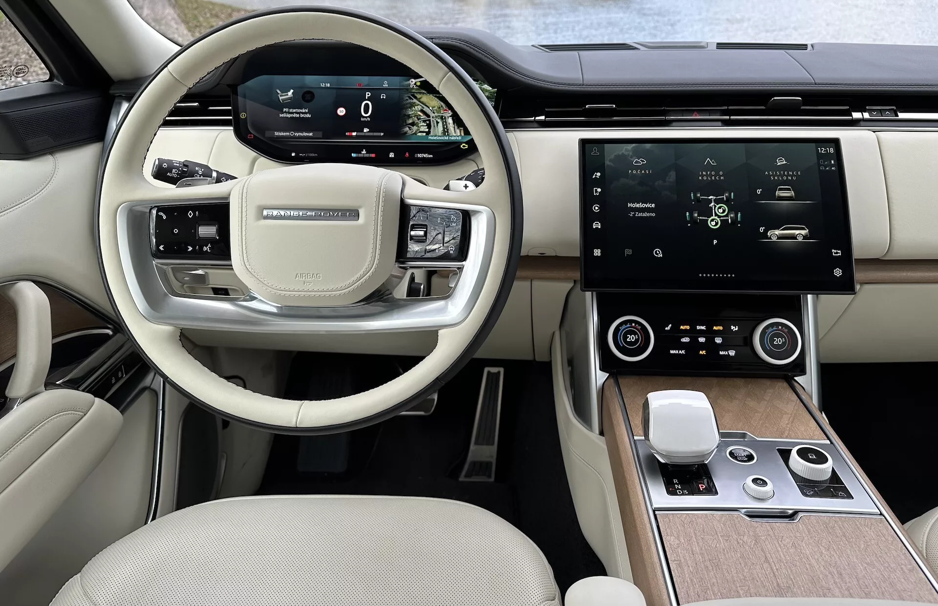 Interiér Land Rover Range Rover 2021 s moderním volantem s multifunkčními tlačítky, digitálním přístrojovým panelem, velkou centrální dotykovou obrazovkou infotainmentu, automatickou klimatizací a luxusním dvoubarevným designem kabiny