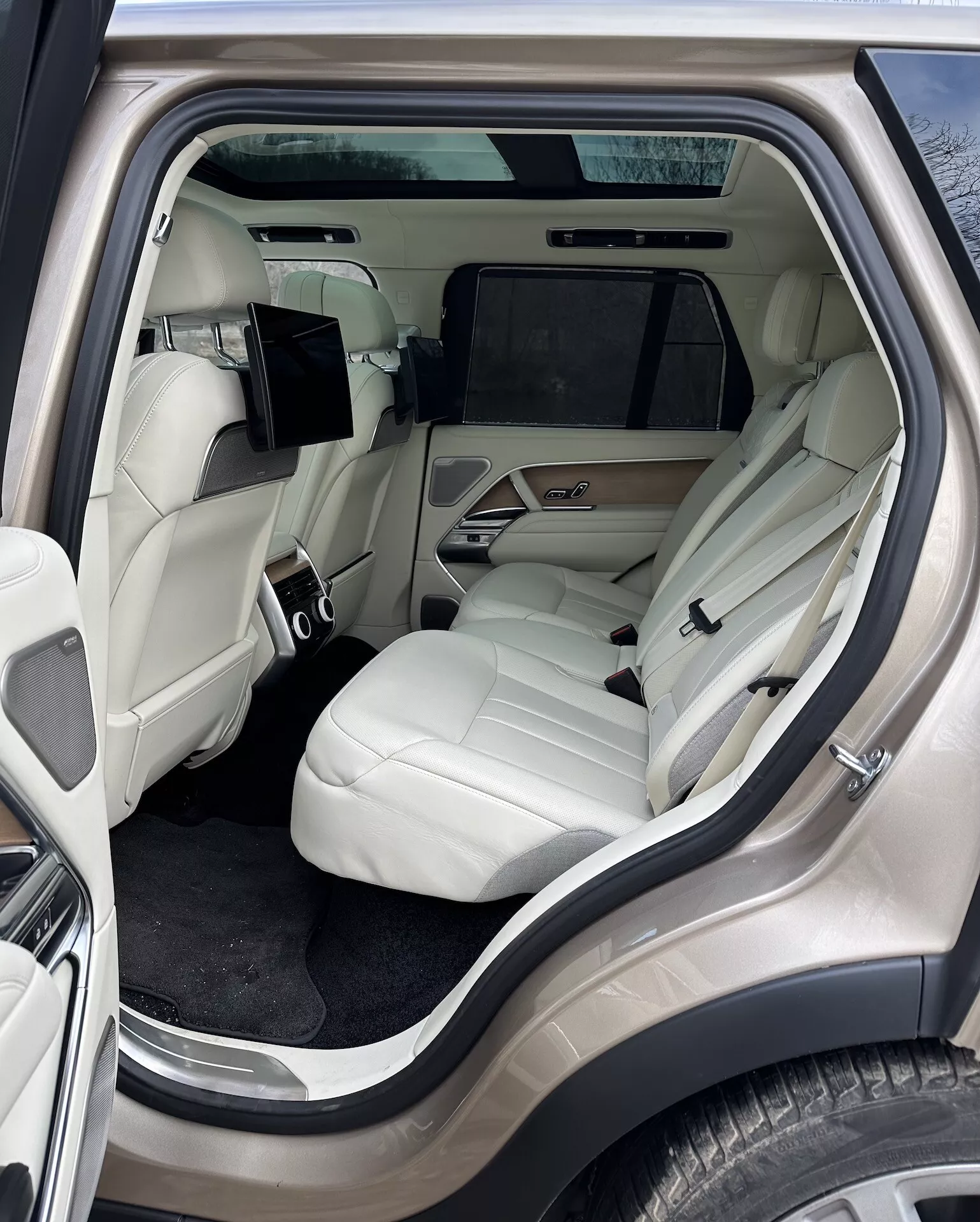 Interiér Land Rover Range Rover 2021 zaměřený na luxusní zadní část pro cestující z bočního úhlu, s ​​světlými koženými sedadly, pokročilou středovou konzolou, zábavním systémem a luxusními detaily