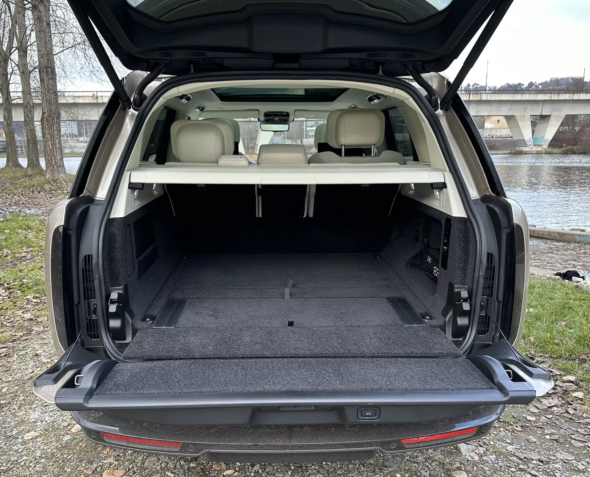 Land Rover Range Rover SUV 2021 ukazující prostorný zadní nákladový prostor s otevřenými zadními vraty, čalounění světlé barvy v kontrastu s tmavým kobercem a interiérové prvky včetně osvětlení nákladového prostoru a možných mechanismů skládání sedadel