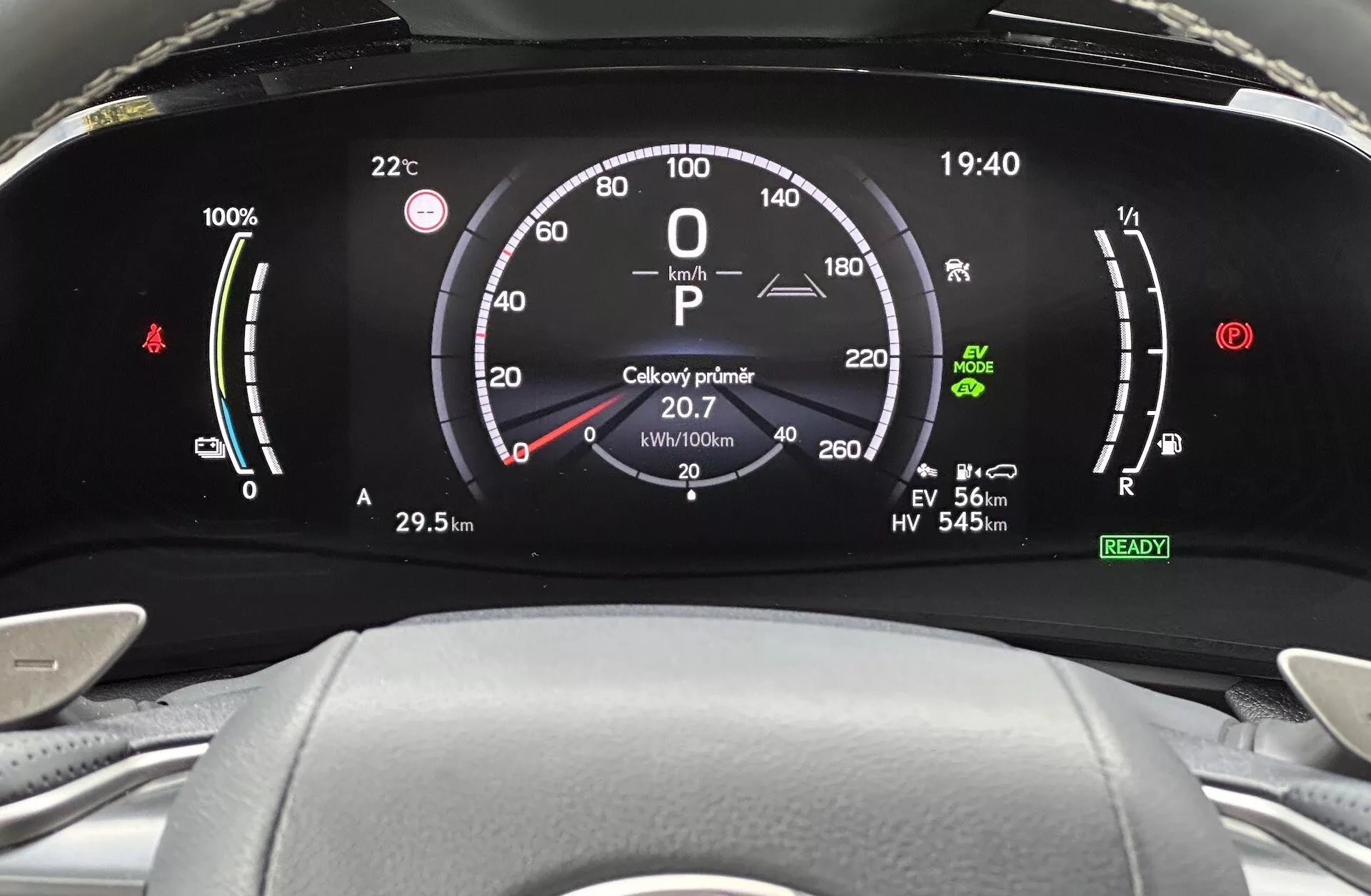 Detailní pohled na digitální přístrojovou desku Lexus NX z roku 2021, zobrazující indikátor nabití baterie, rychloměr, ukazatel výkonu a různé indikátory řídících režimů z pohledu řidiče.