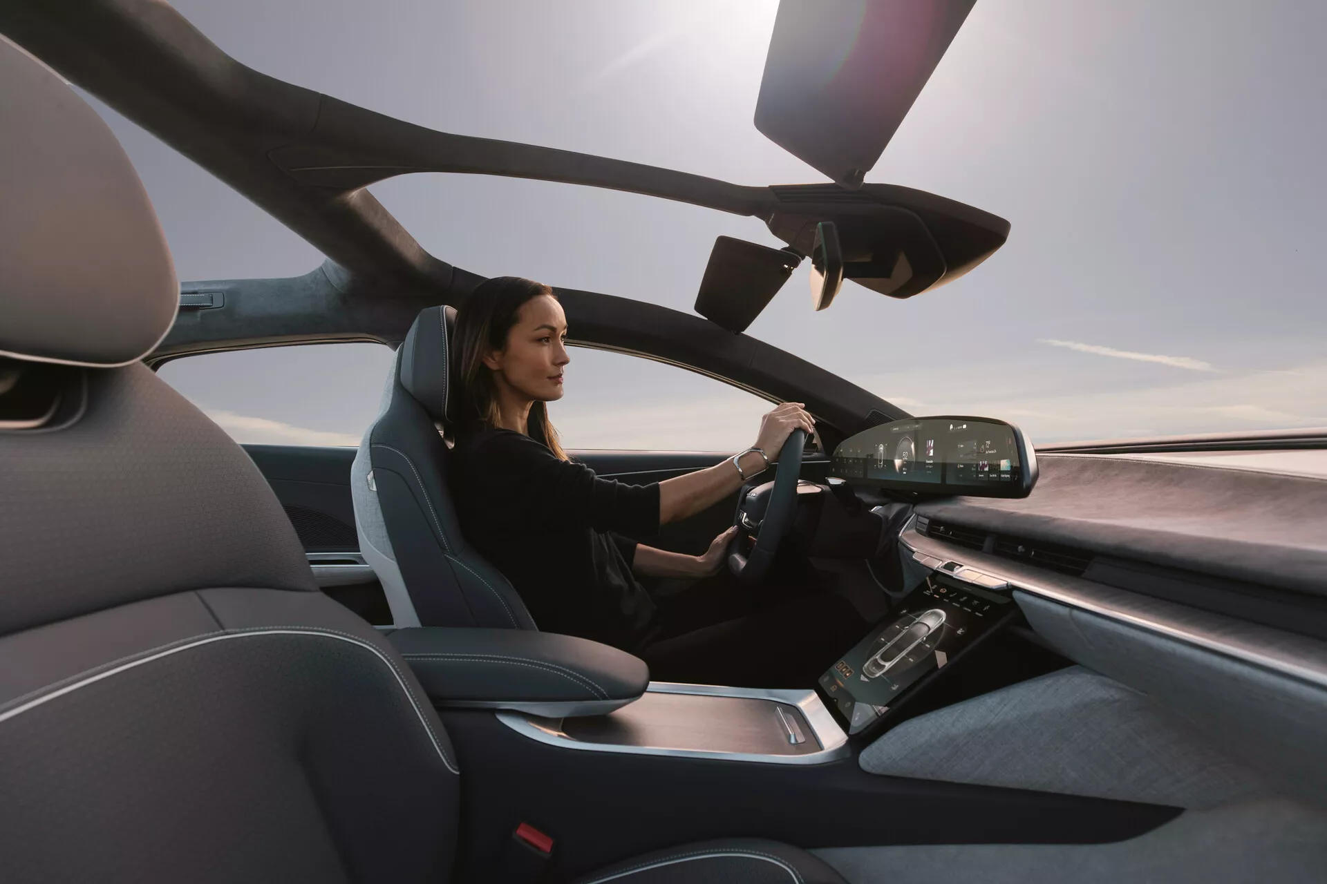 Pohled do interiéru Lucid Air 2022 z místa spolujezdce, který ukazuje moderní sedadlo řidiče a pokročilou přístrojovou desku s digitálními displeji a dotykovými ovládacími prvky, zdůrazňující luxusní a technologicky vyspělý design
