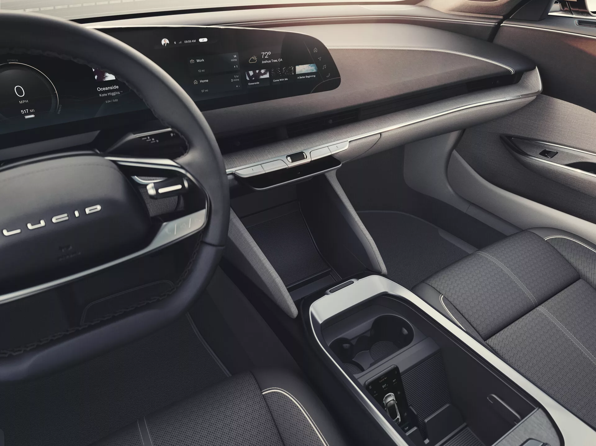 Pohled na interiér Lucid Air 2022 (1. generace) ze zadního sedadla, ukazující elegantní palubní desku s nepřerušeným digitálním displejem, moderní volant s vestavěnými ovládacími prvky, luxusní materiály, středový dotykový displej a volič převodovky v centrální konzole, ergonomické přední sedadlo pro spolujezdce, pokročilé ovládání oken a zrcátek na dveřích spolujezdce, celková atmosféra indikující možnosti ambientního osvětlení.