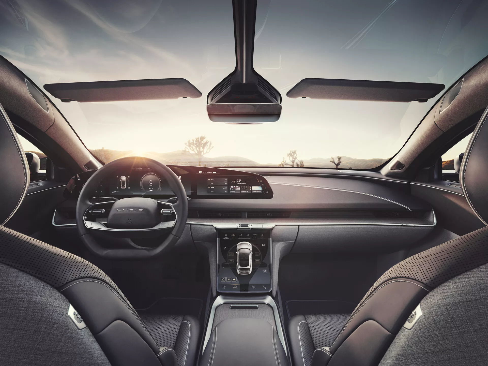 Pohled na interiér vozu Lucid Air 2022 ze zadního sedadla, předvádějícího palubní desku, infotainment displej, digitální přístrojový panel a kožené a prémiové materiály, což naznačuje vyšší model s pokročilým mediálním systémem, ovládáním klimatu a technologiemi konektivity.