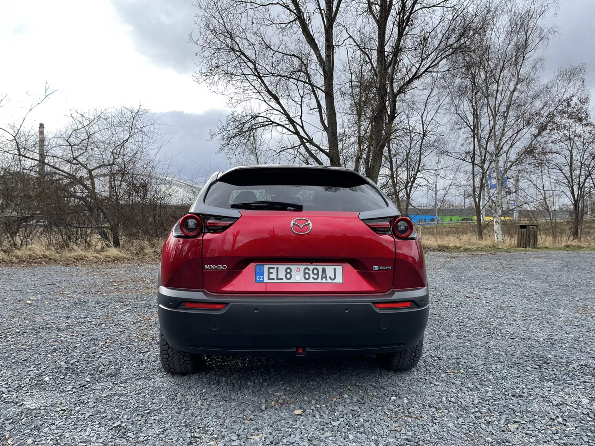 Mazda MX-30 roku 2020 v elegantní kovové barvě, která předvádí její moderní design a elektrickou technologii, zaparkovaná na malebném místě