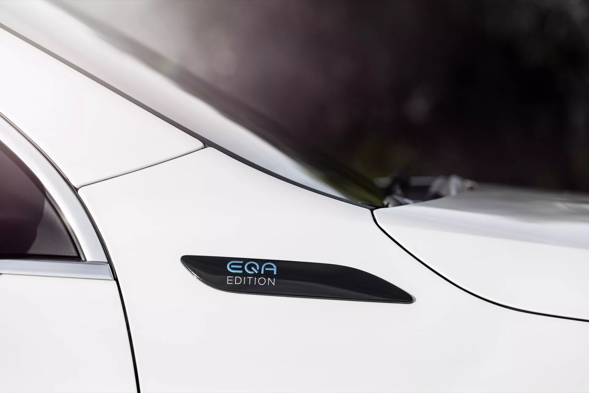 Detailní záběr na Mercedes-Benz EQA 2021 ukazující elegantní boční profil v oblasti zadních dveří a blatníku, s důrazem na bílou barvu, označení 'EQE EDITION', design bez kličky u dveří a linie návrhu naznačující moderní estetiku a pokročilou technologii.