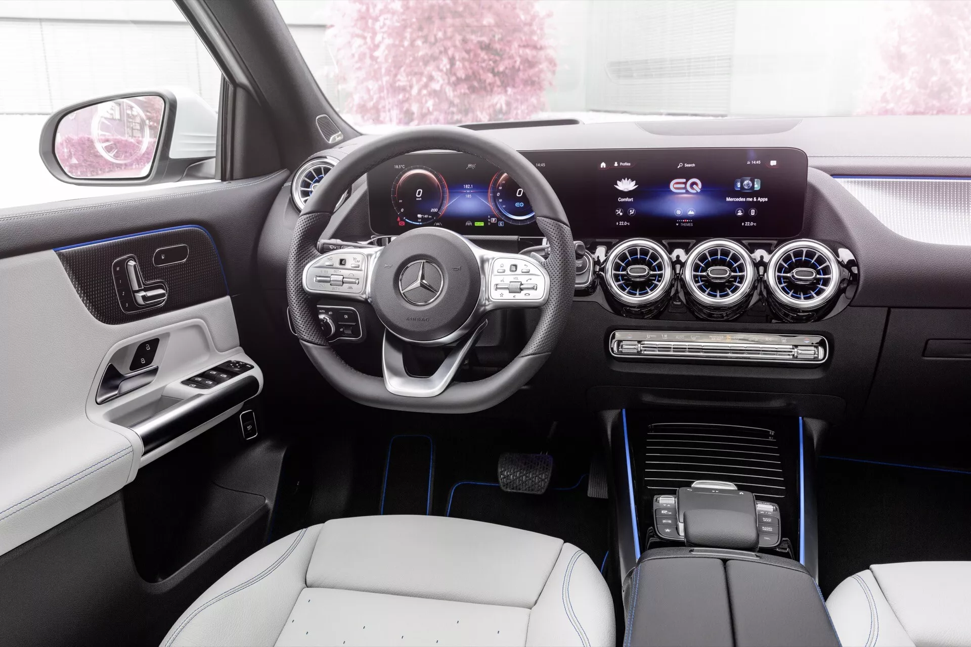 Interiérový pohled na Mercedes-Benz EQA 2021 ukazující elegantní palubní desku, digitální přístrojový panel, multifunkční volant a centrální dotykový informační systém z perspektivy zadního sedadla