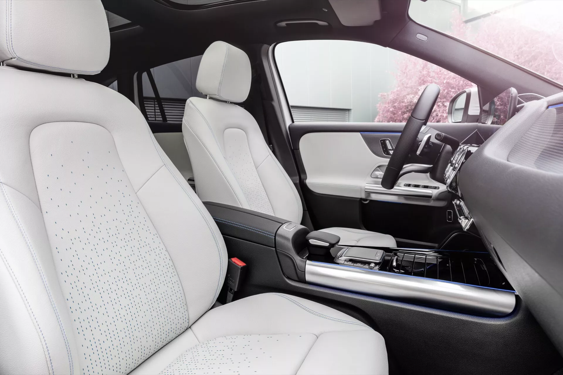 Pohled do interiéru Mercedes-Benz EQA 2021 zdůrazňující oblast sedadla spolujezdce, přední palubní desku, centrální konzolu a sedadla potažená bílou perforovanou kůží naznačující technologii ventilovaných sedadel pro další pohodlí, integrovaná s pokročilým informačním systémem a prvky luxusního designu.