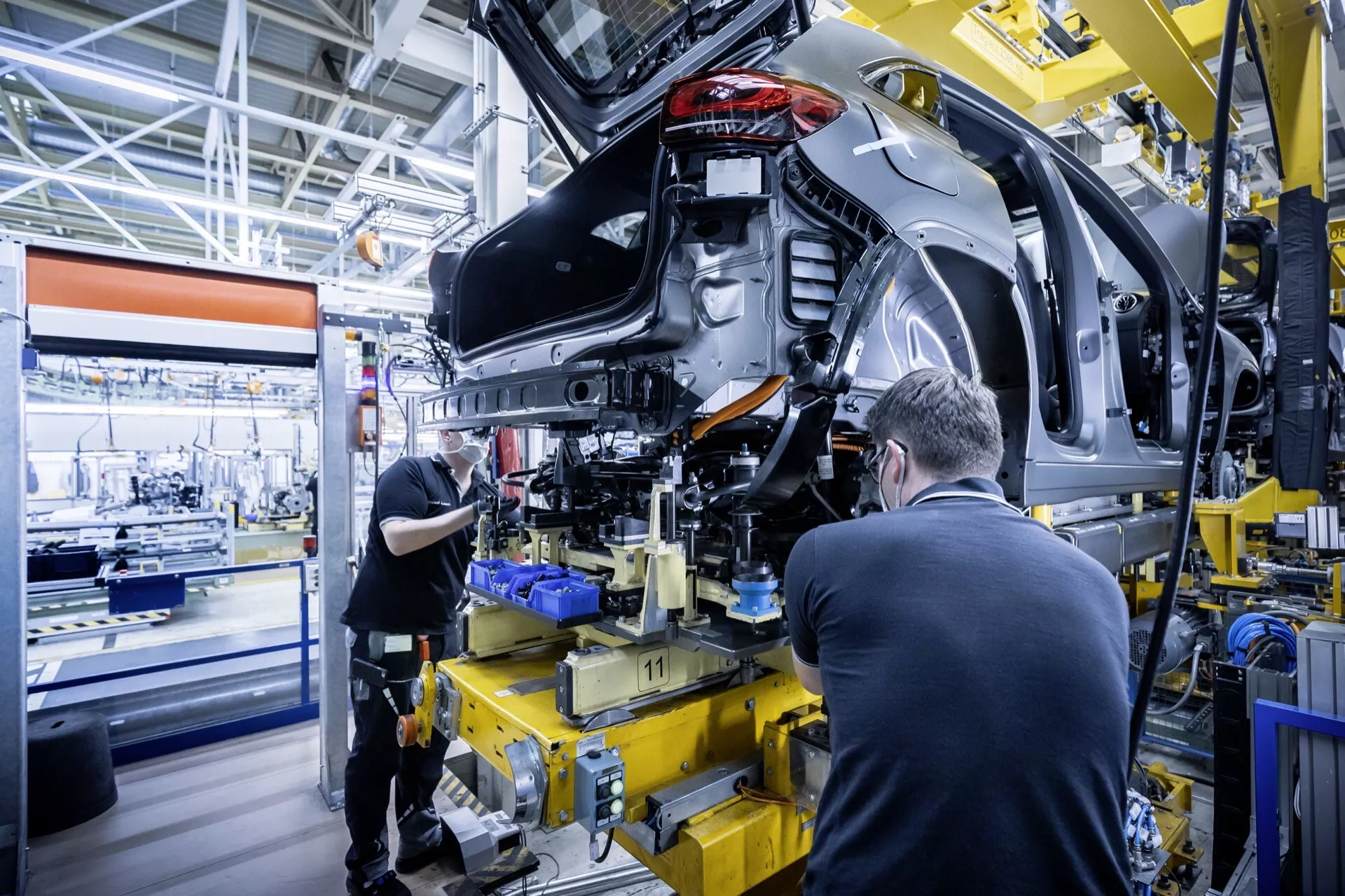 Mercedes-Benz EQA z roku 2021 (243) ve střední fázi montáže, zobrazení zadního levého kvartálu s odkrytými vnitřnostmi a zavěšením, v moderním výrobním závodě automobilů
