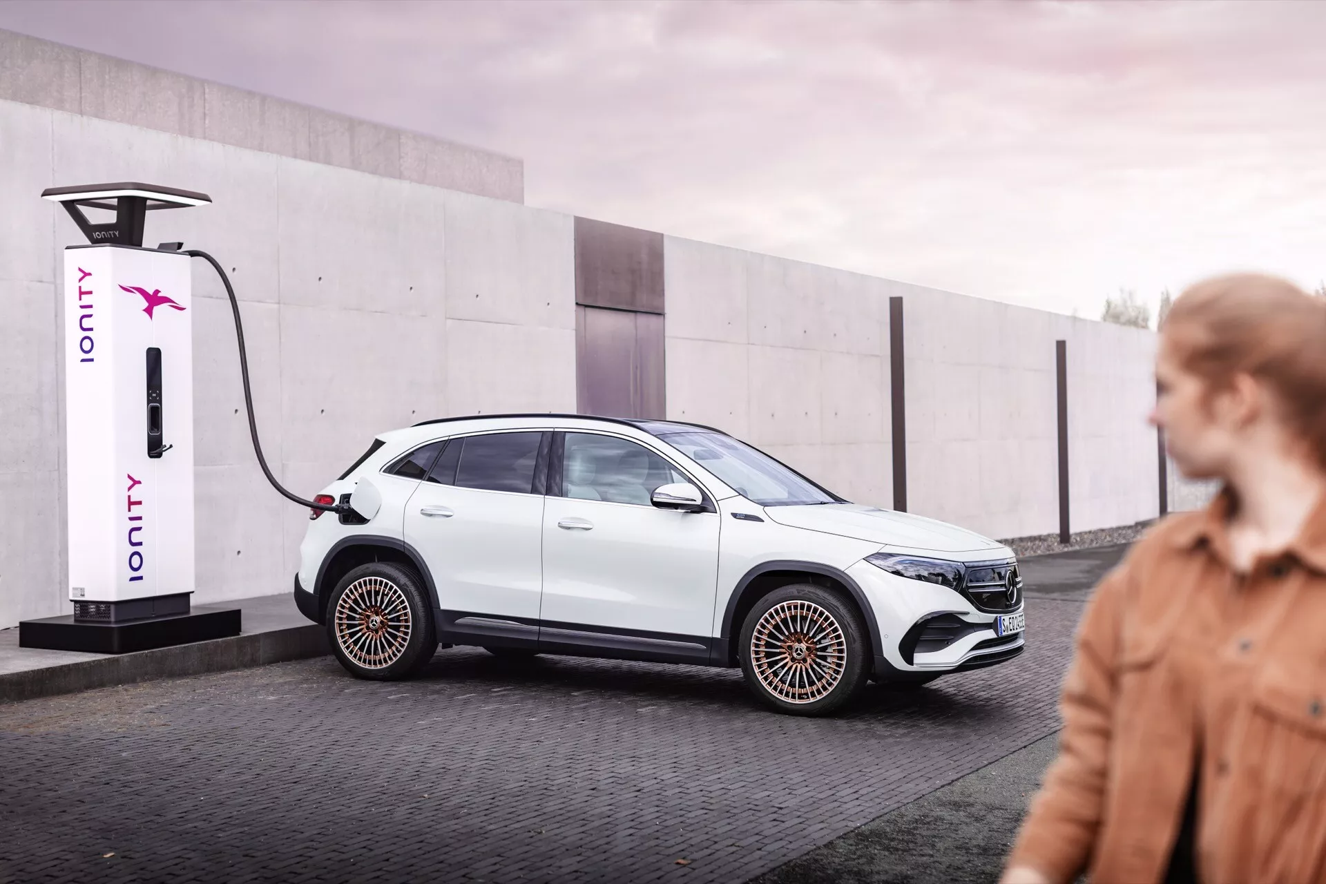 Elektrické auto Mercedes-Benz EQA 2021 připojené k nabíjecí stanici IONITY, prezentující elegantní design a aerodynamické prvky v městském prostředí