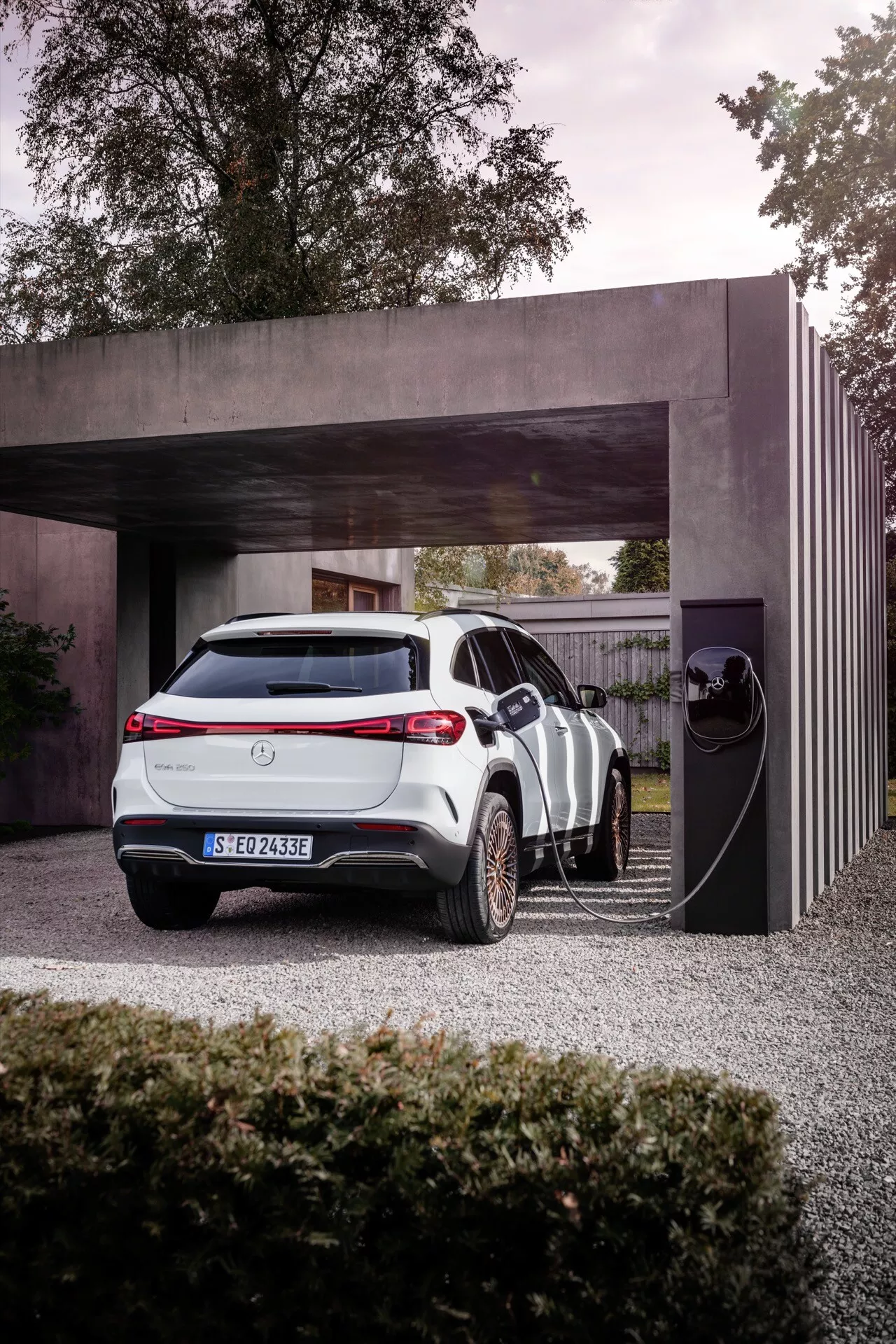 Elektrické vozidlo Mercedes-Benz EQA 2021 zaparkované u soukromé nabíjecí stanice, zdůrazňující jeho elegantní design a moderní technologické funkce na pozadí současné architektury