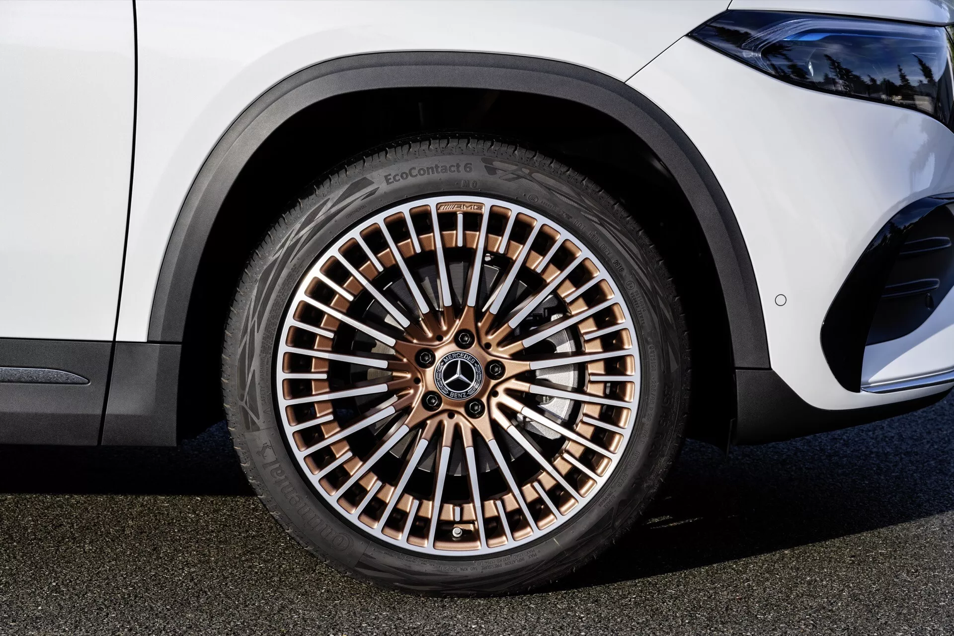 Detailní pohled na kolo Mercedes-Benz EQA 2021 s vícepaprskovým ráfkem v bronzovém tónu a vysokoprofilovou pneumatikou EcoContact, odrážející luxusní a ekologické designové prvky