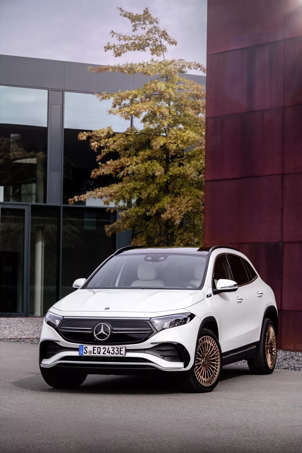 Bílé SUV Mercedes-Benz EQA 2021 zaparkované v městském prostředí ukazuje přední mřížku, LED světlomety, sportovní nárazník a vícepaprsková slitinová kola z nízkého úhlu přední tříčtvrteční pohledu, což zdůrazňuje pokročilý design a funkce elektrického pohonu.