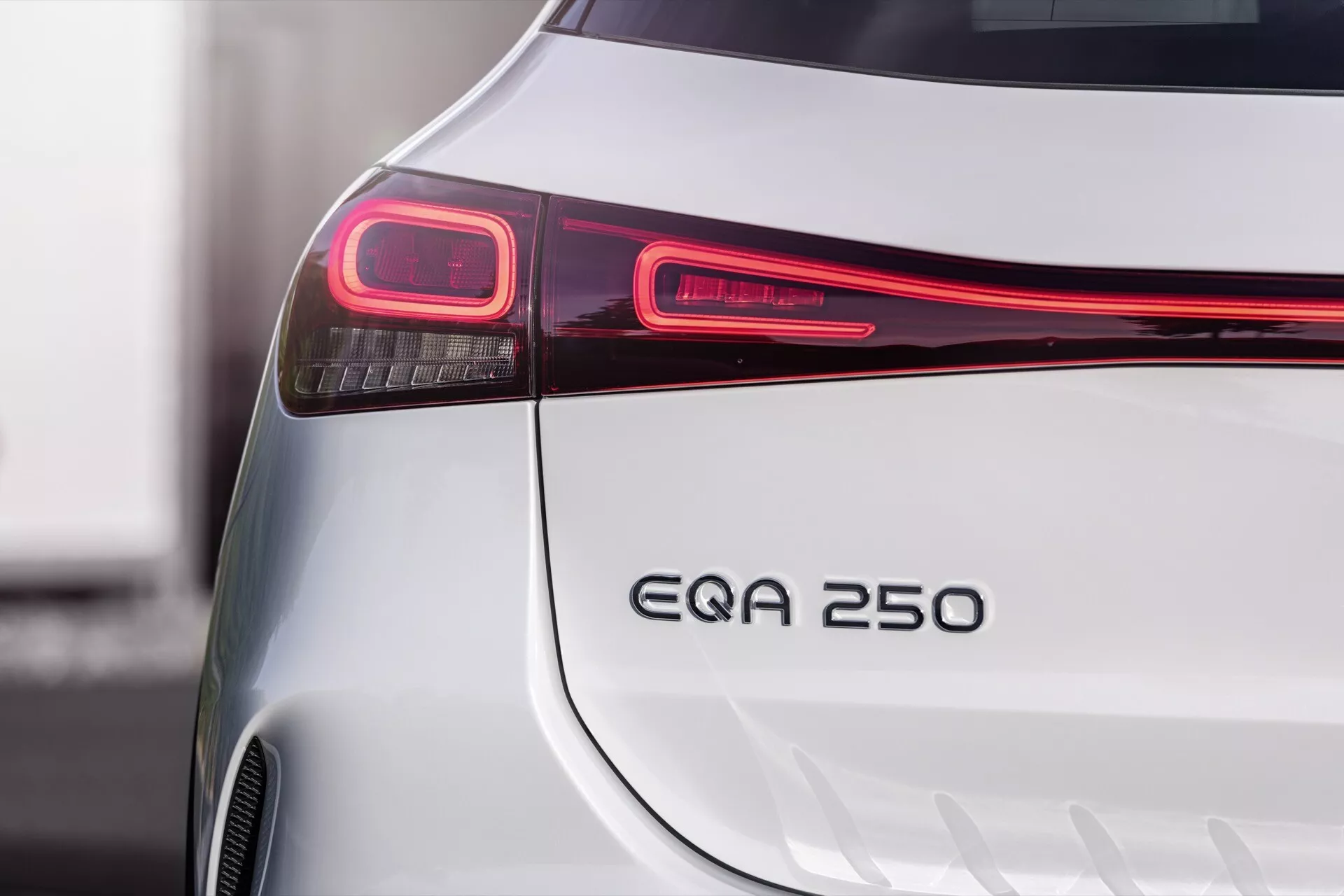 Detailní snímek zobrazující elegantní zadní část stříbrného Mercedes-Benz EQA 2021, zdůrazňující jeho moderní LED zadní světlo, označení modelu EQA 250 a design nárazníku, což naznačuje jeho status elektrického vozidla