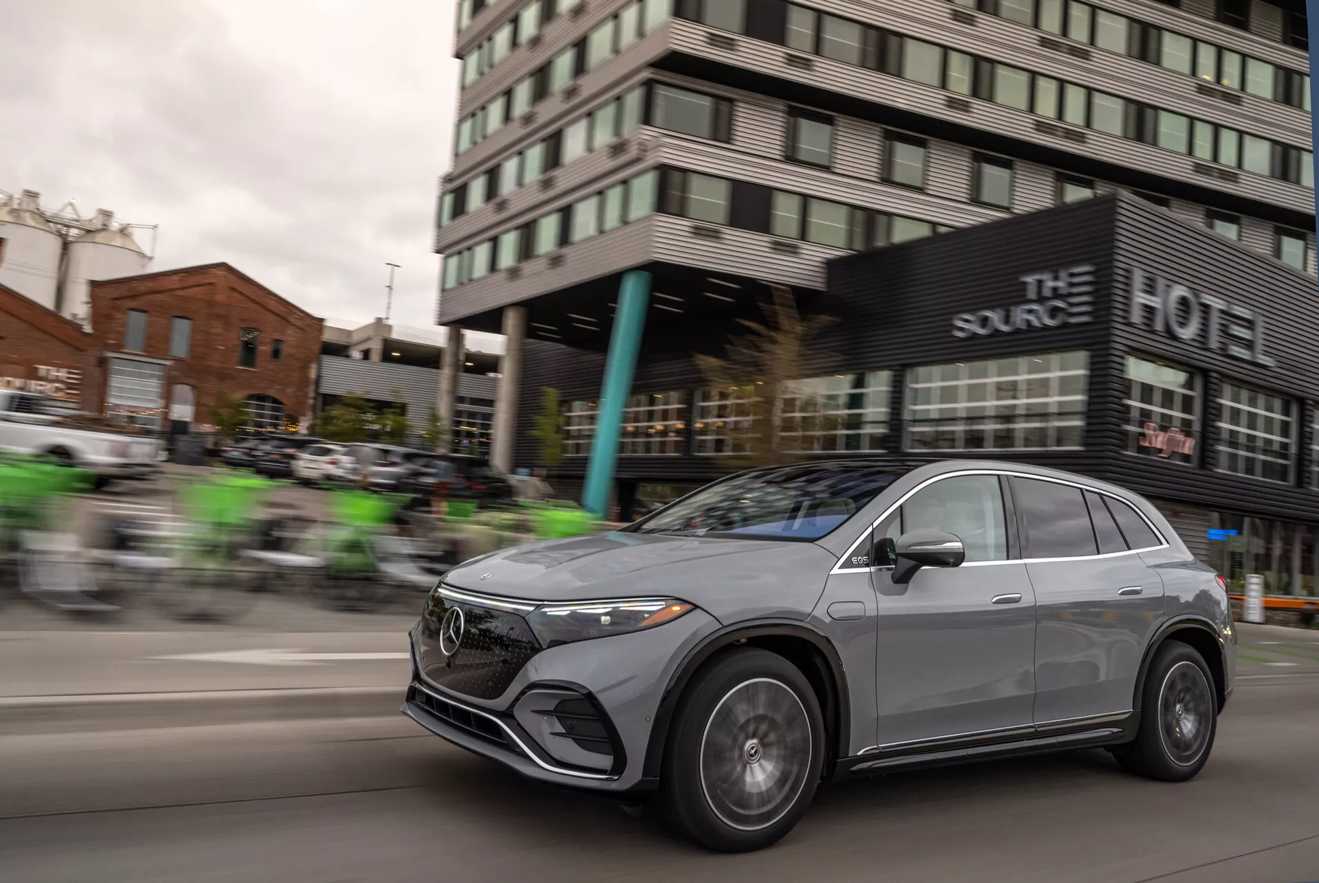 Dynamický záběr Mercedesu EQS-SUV 2022 v pohybu, s efektem rozmazání, který zdůrazňuje rychlost vozidla. Výrazné jsou přední mřížka, LED světlomety, litá kola a aerodynamický design kapoty a střešní linie, což podtrhuje sofistikované a luxusní prvky vozidla. Kovový povrch a crossover styl s elegantními beztíženými okny a aerodynamicky tvarovanými zrcátky přidávají moderní a prémiový vzhled.