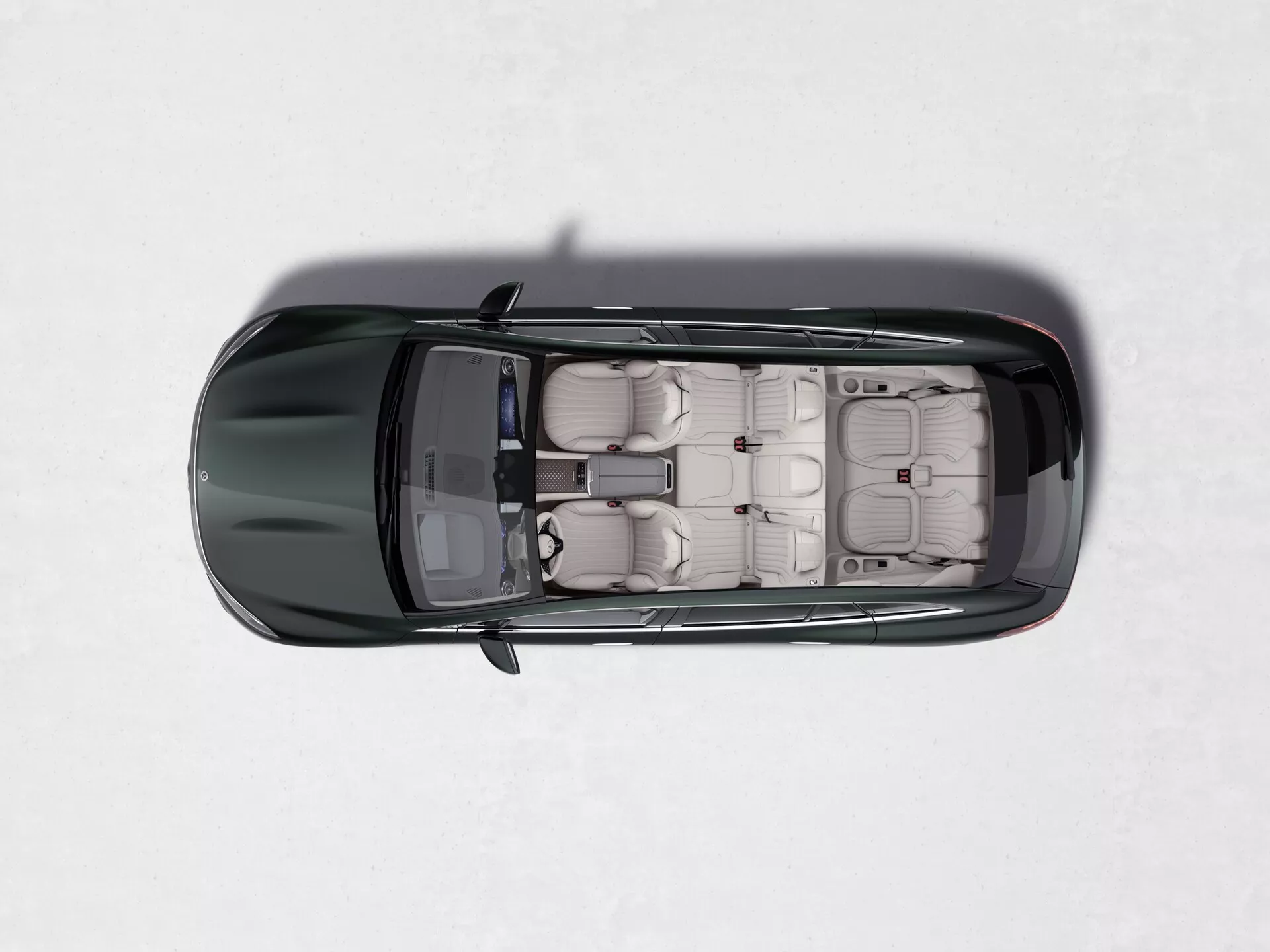 Pohled shora na Mercedes EQS SUV 2022, který ukazuje jeho střešní okno, světlé kožené čalounění, jednotlivá sedadla s opěrkami hlavy, čtyři dveře se zapuštěnými klikami, lesklý tmavý lak a kontrastní boční zrcátka na světlém, jednotném pozadí.