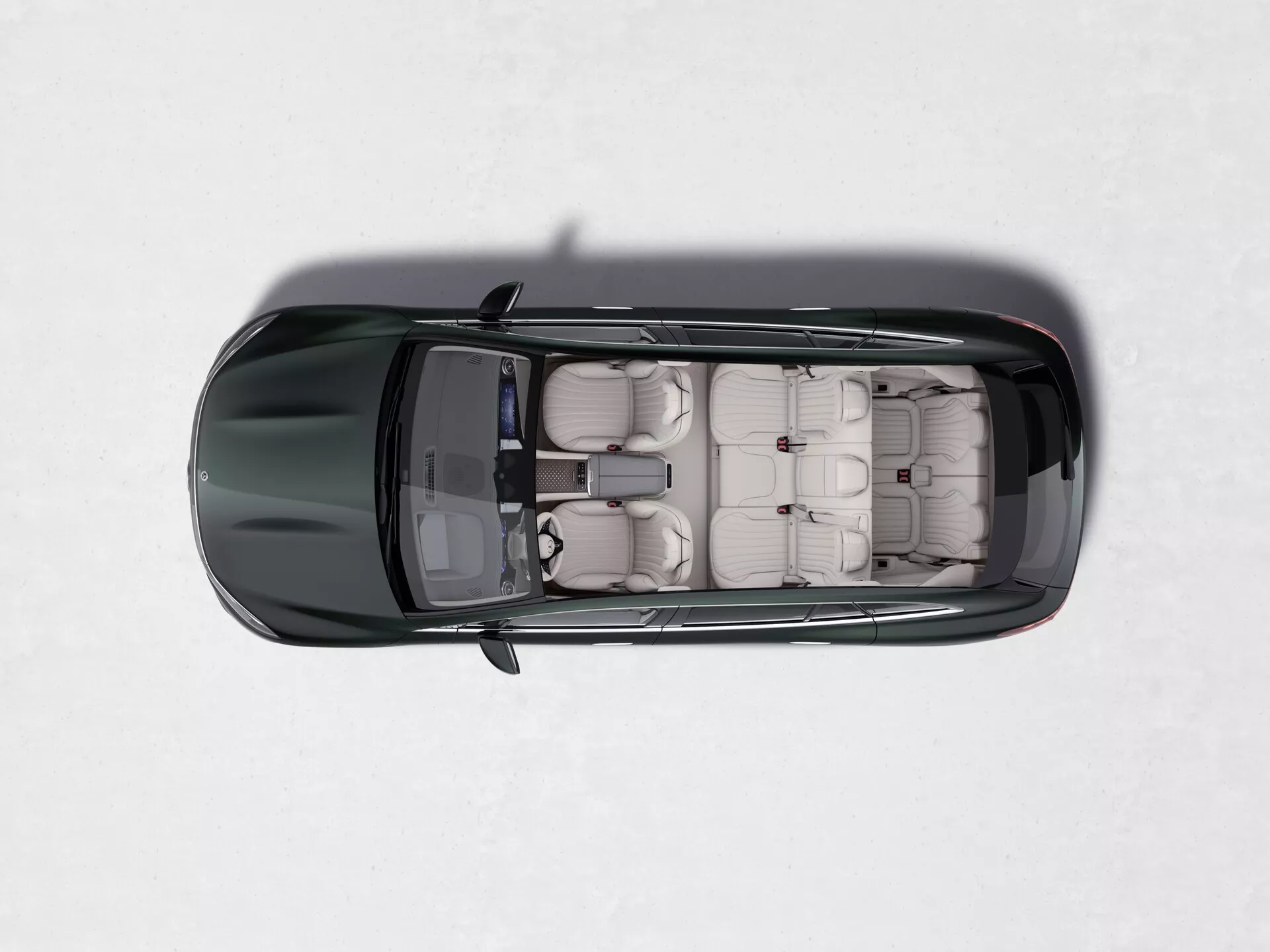 Pohled shora na tmavou barvu Mercedes EQS-SUV 2022 na lehkém, zasněženém povrchu. Obrázek ukazuje plně otevřené střešní okno, odkud je vidět béžový nebo béžový kožený interiér se třemi řadami sedadel, což zdůrazňuje jeho kapacitu pro větší počet cestujících, pravděpodobně SUV.