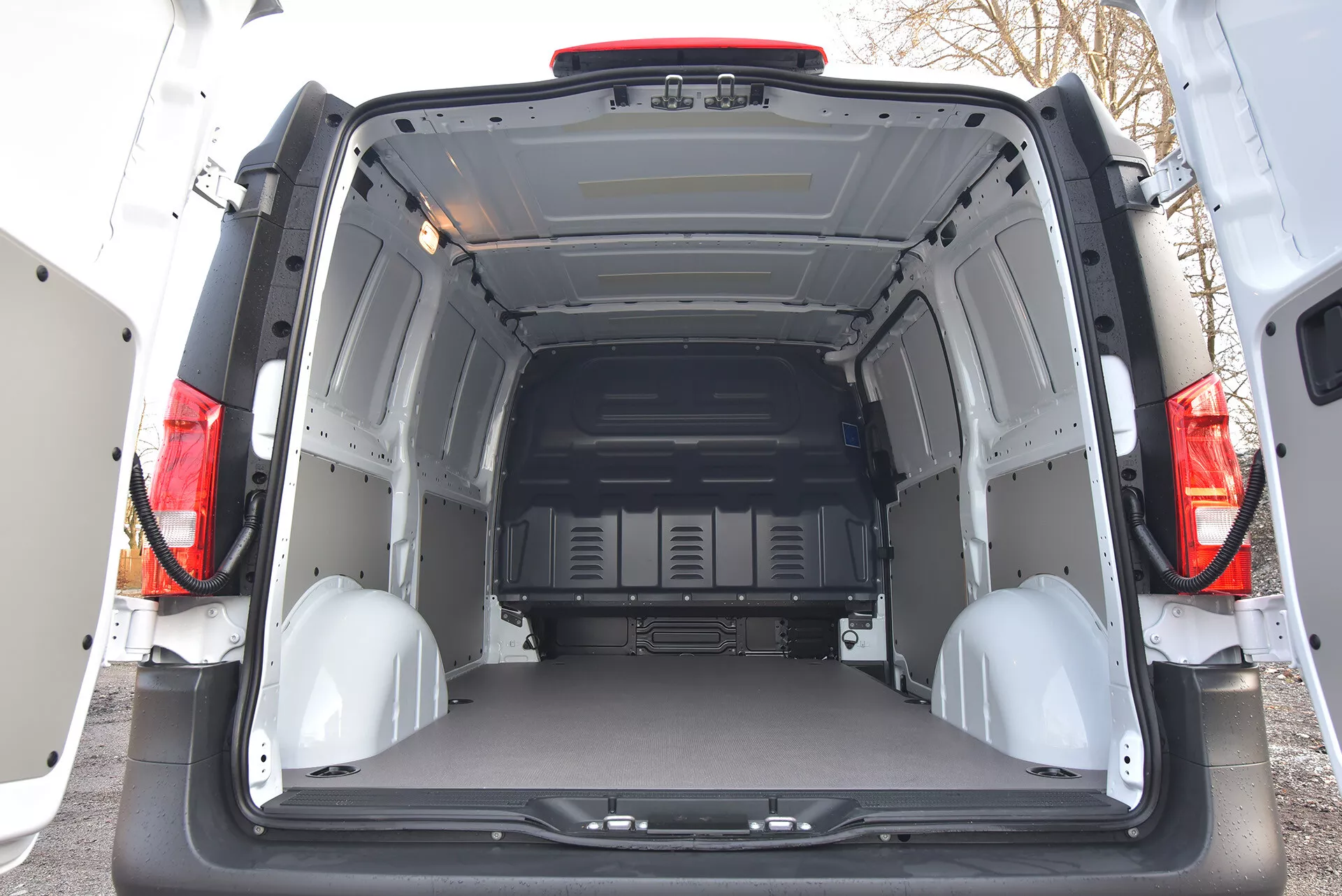 Zadní interiérový pohled na Mercedes-Benz Vito Tourer z roku 2014 ukazující prostorný a prázdný nákladní prostor s otevřenými dveřmi, ochrannými panely a bodů pro upevnění nákladu