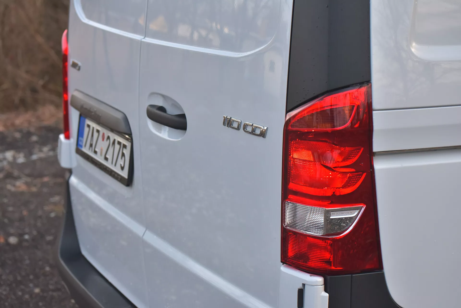 Pohled na zadní pravý roh stříbrného nebo světle šedého Volkswagen Vito 2014 Tourer se zobrazením zadního světla, označení modelu 'VW CADDY', evropské registrační značky '12-TZ-4715' a designu karoserie typického pro kompaktní nákladní dodávky.