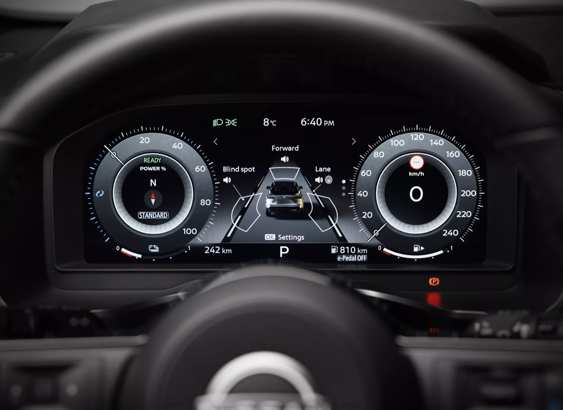 Pohled na interiér zaměřený na digitální přístrojovou desku Nissan Qashqai 2024 (J12-facelift) z perspektivy řidiče. Displeje zahrnují kruhový rychloměr až na 240 km/h, otáčkoměr s 'N' pro neutrální převodovku, 'POWER' lištu, grafické auto s pruhovými indikacemi, monitorování 'Mrtvý úhel', 'Forward' upozornění na kolizi, 'Lane' asistenci, venkovní teplotu (8°C), hodiny (18:40), indikaci parkovací brzdy a počítadlo kilometrů zobrazující 242 km ujeté vzdálenosti a dojezd 810 km. Rozmazané pozadí zdůrazňuje přístrojovou desku.