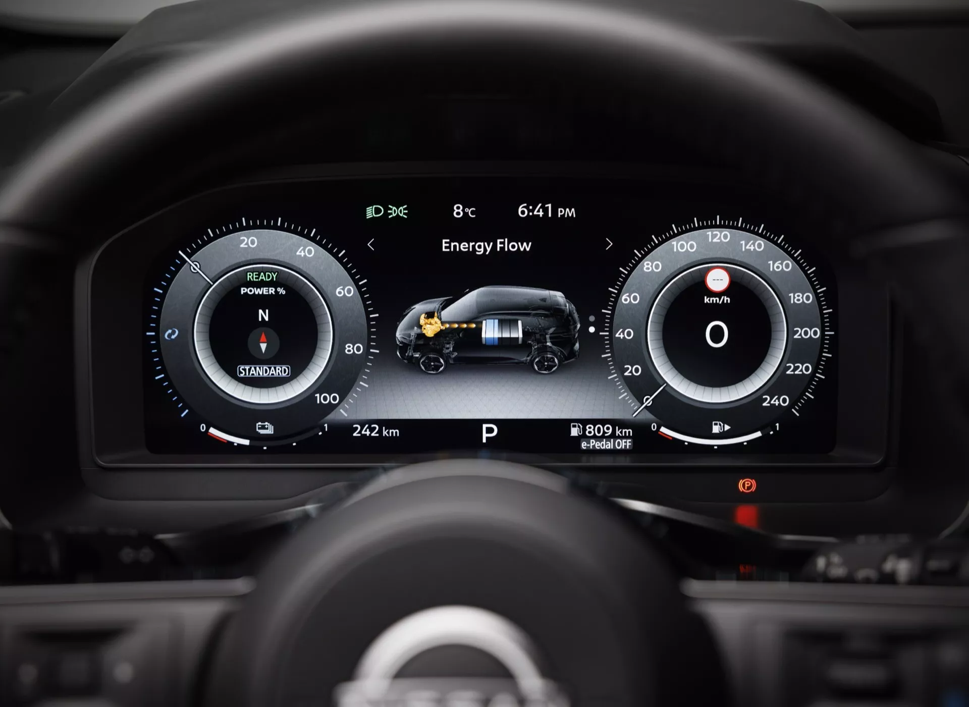 Pohled z pozice řidiče na digitální přístrojový panel Nissan Qashqai 2024 (J12-facelift) s pokročilou technologií, dvěma digitálními obrazovkami zobrazujícími rychloměr, ukazatel výkonu, otáčkoměr, tok energie hybridní pohonné jednotky a různé provozní údaje včetně venkovní teploty, času a celkového dojezdu.