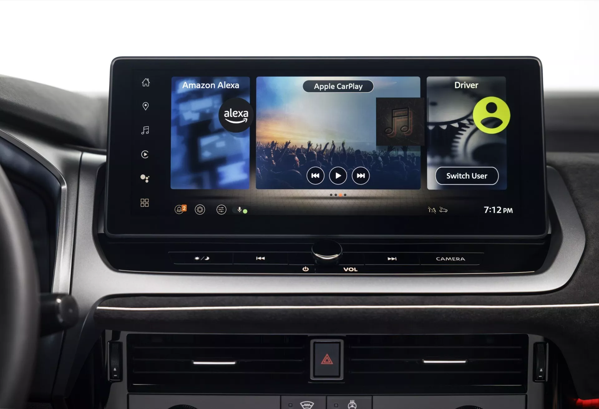 Detailní pohled na interiér modelu 2024 Nissan Qashqai (J12-Facelift) se zaměřením na pokročilý infotainment systém a oblast palubní desky. Velký moderní dotykový displej uprostřed konzole zobrazuje ikony pro Amazon Alexa a Apple CarPlay, což naznačuje rozšířené možnosti konektivity. Vpravo od obrazovky se nachází štítek 'Řidič' a funkce 'Přepnout uživatele', což naznačuje možnosti přizpůsobení pro více řidičů, čas ukazuje 19:12. Níže jsou viditelné tlačítka a otočné voliče pro hlasitost a další funkce spolu s tlačítkem výstražných světel označeným červeným trojúhelníkem. Materiály a povrchové úpravy prvotřídní kvality naznačují prémiový interiér vozidla.