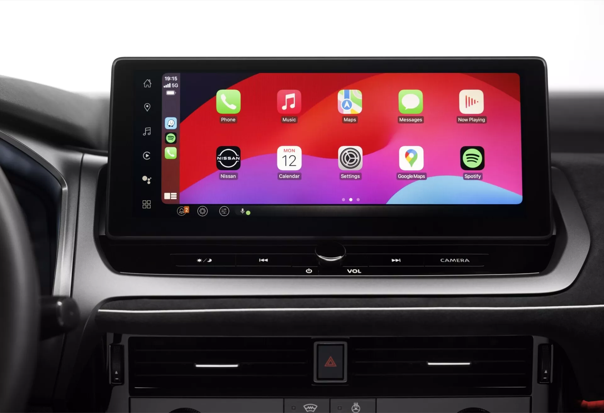 Detailní pohled na středovou palubní desku uvnitř vozu Nissan Qashqai 2024 (J12-facelift), zaměřený na velký horizontální dotykový infotainment systém zobrazující barevné rozhraní připomínající uživatelské prostředí smartphonu. Pod obrazovkou jsou viditelné fyzické tlačítka a CD/DVD slot, s tlačítkem výstražných světel uprostřed. Obrázek zvýrazňuje pokročilé možnosti zábavy a konektivity tohoto moderního vozu.