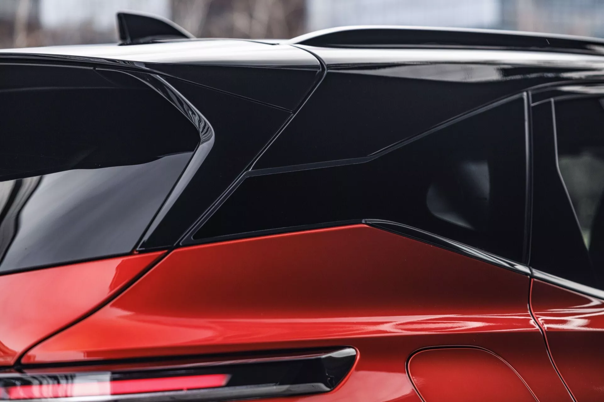 Detailní pohled na zářící červený Nissan Qashqai 2024 (J12-facelift) zdůrazňující designové prvky a potenciální technologické funkce ze zadní čtvrtiny. Zvýrazněno je lesklé provedení, moderní LED zadní světlo s možnými dynamickými směrovkami, integrovaný zadní spoiler, odmrazovací zadní okno, žraločí ploutev antény pro GPS nebo satelitní rádio, hladké tvarované panely karoserie s výrazným záhybem, plynule navazující zadní boční okno a zadní sklo, černé lišty oken a pilíře pro vzhled „plovoucí střechy“ a současné úzké prodloužené zadní světlo.
