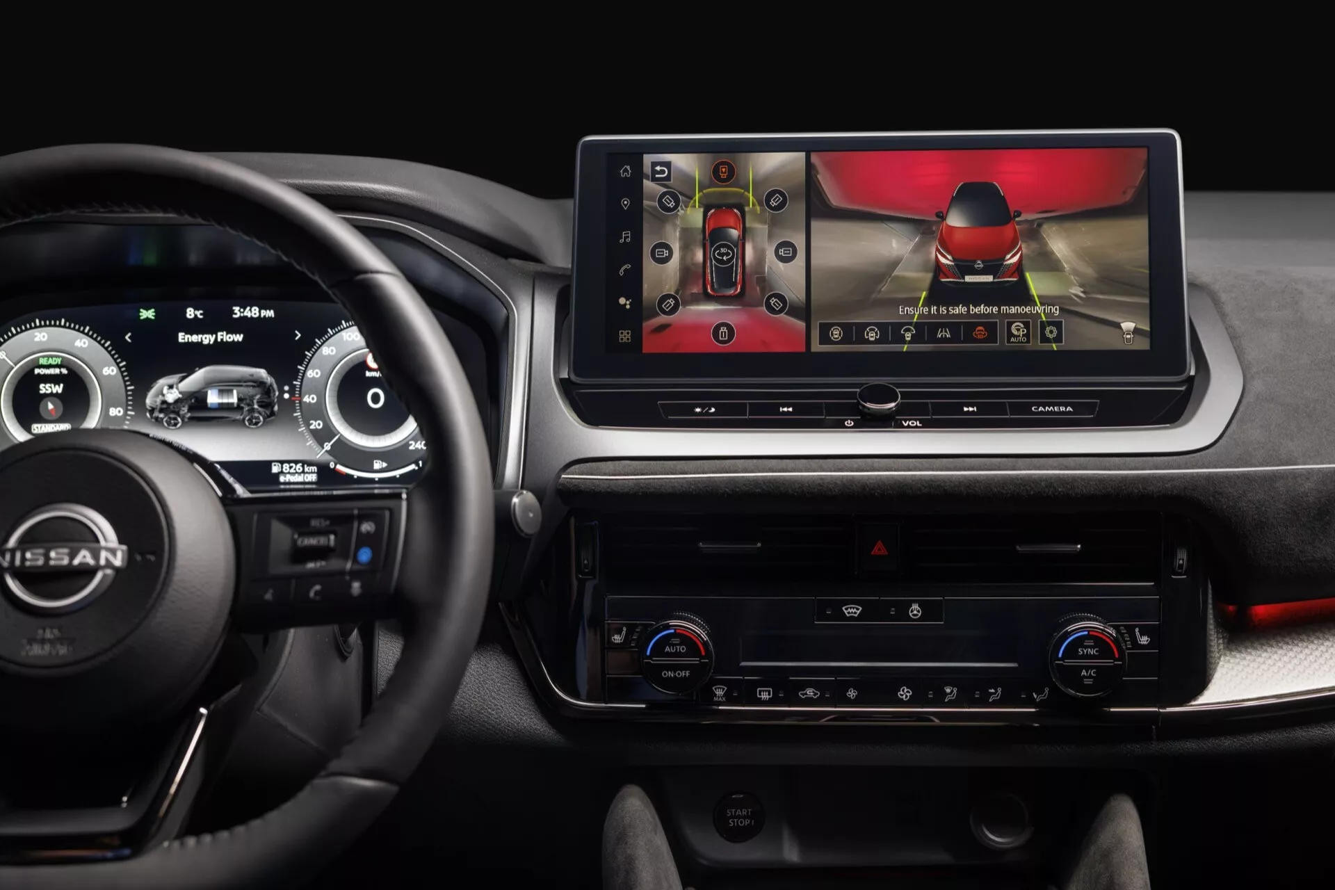 Pohled na interiér Nissan Qashqai 2024 (J12-facelift) zaměřený na přístrojovou desku z pohledu řidiče, zobrazující digitální přístrojový panel, velký tabletový infotainment displej zobrazující zpětnou kameru s dynamickými směrnicemi, klimatizační systém s nastavením pro dvě zóny, fyzickými tlačítky a knoflíky, a měkkými materiály s červenými akcenty. Obrázek poskytuje moderní, technicky orientovaný zážitek z automobilu.
